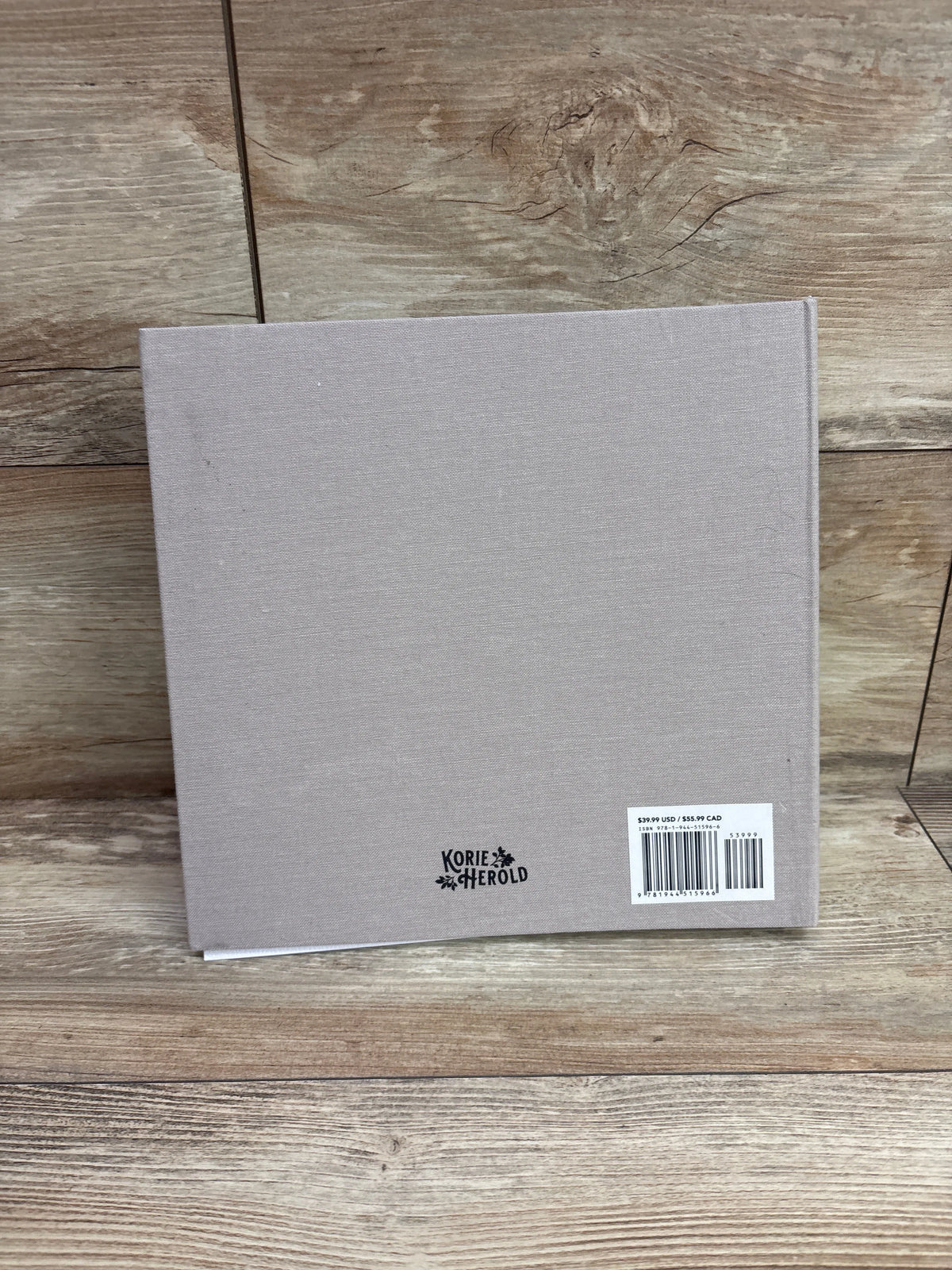 Back view of Growing Up memory book showcasing gray fabric cover and Korie Herold logo on a wood surface