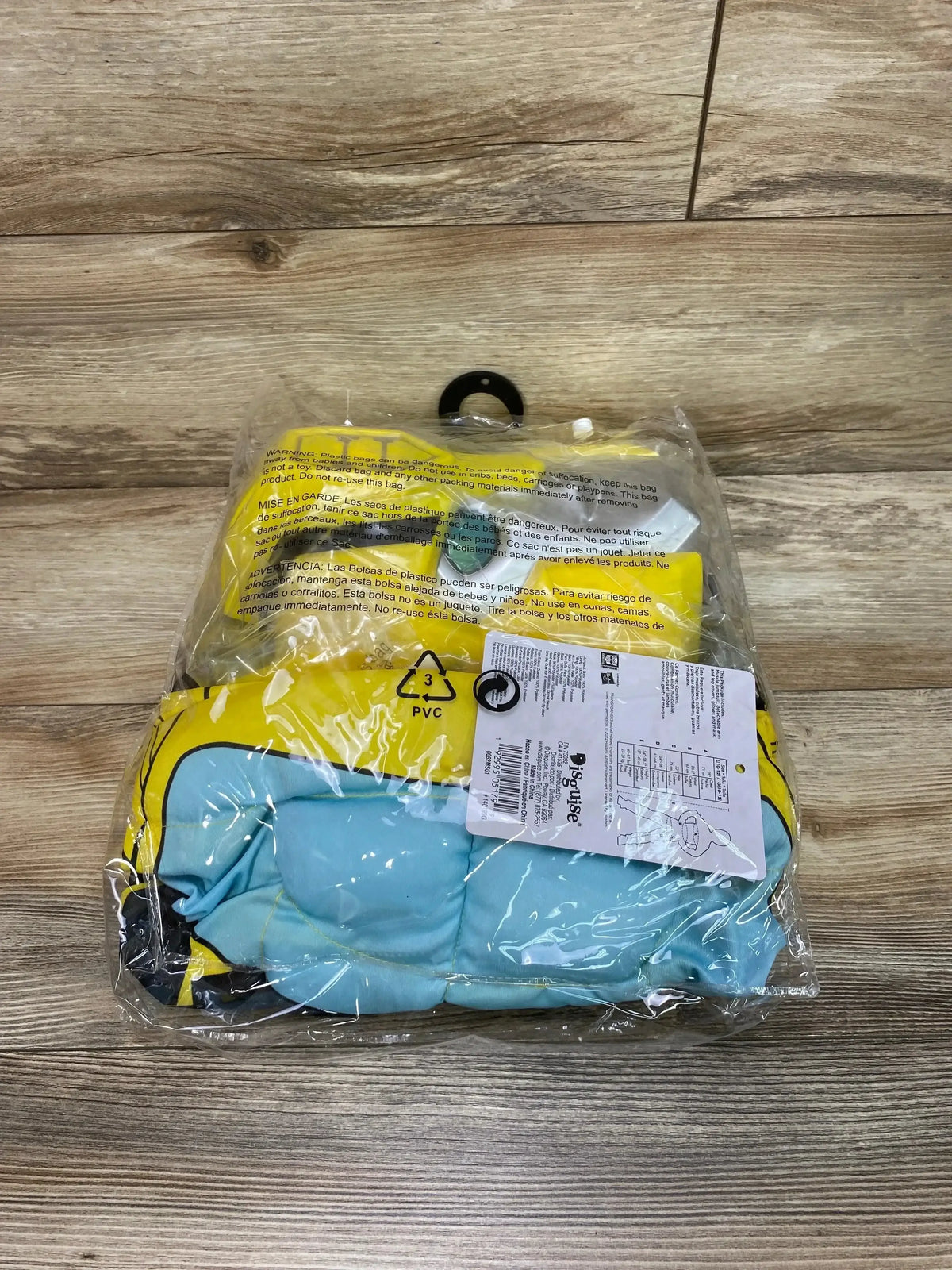 Packaged Transformers Bumblebee costume in yellow and blue, shown in a clear plastic bag on a wood-look floor
