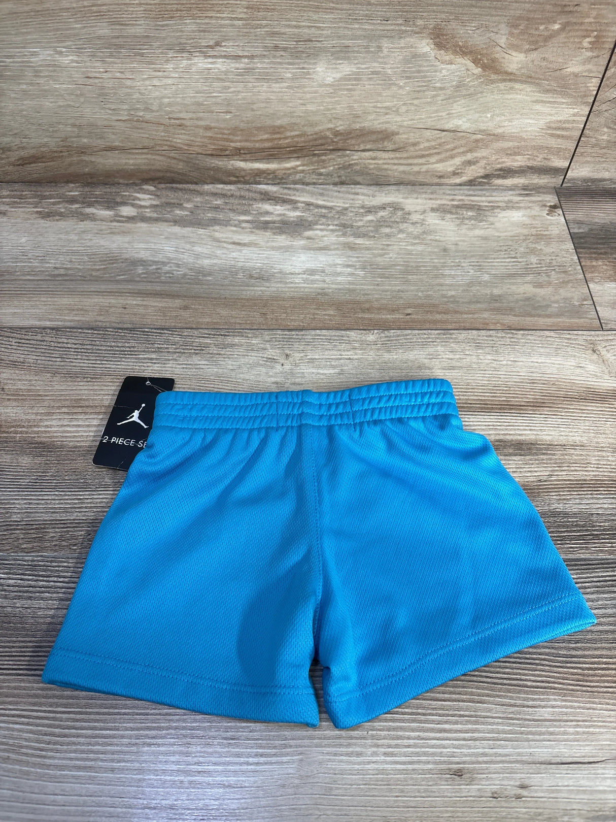 Flat-lay of Air Jordan blue mesh baby shorts size 12 months showcasing elastic waistband and Jordan tag on wood background