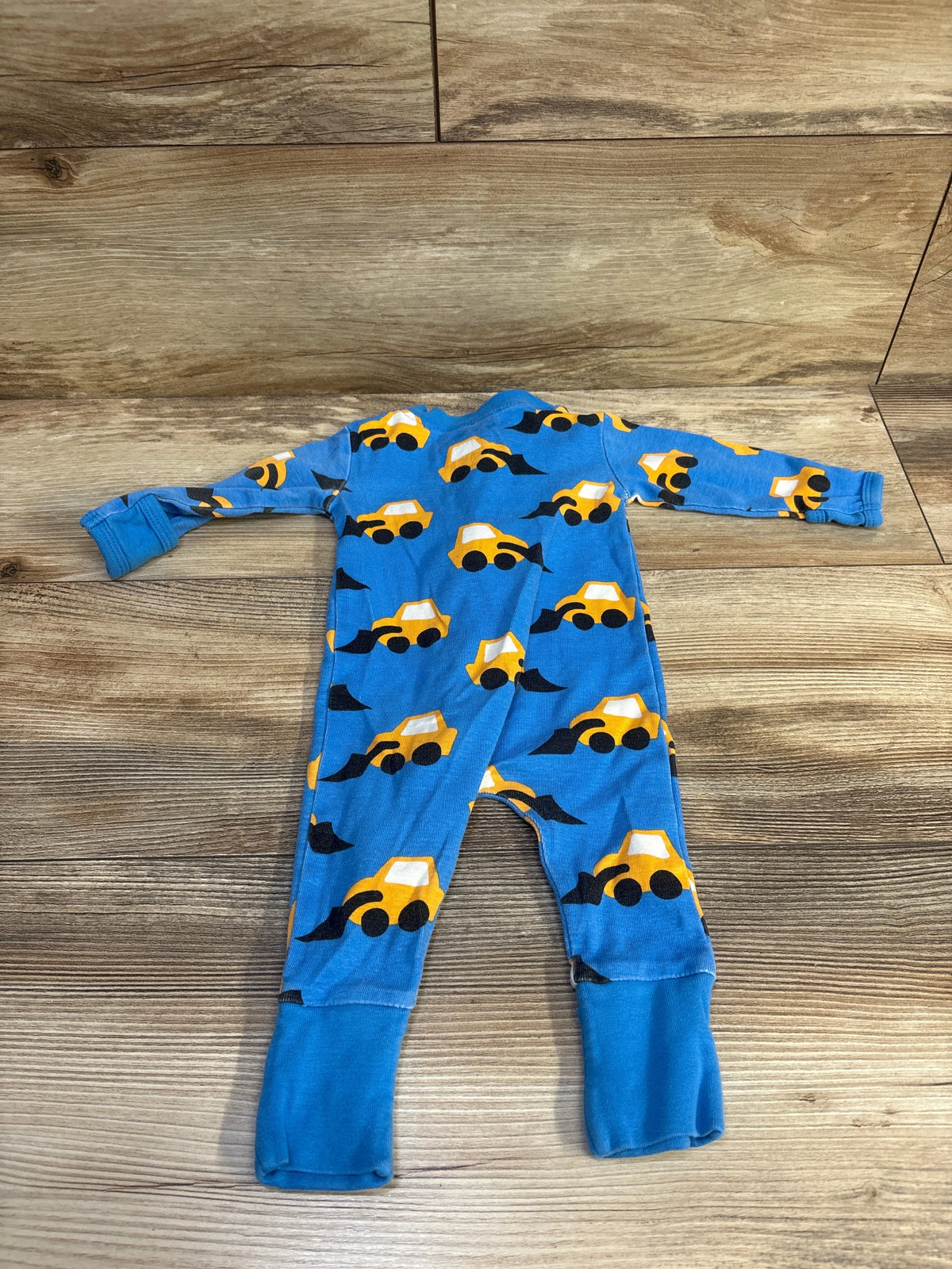 Front view of blue convertible baby sleeper with long sleeves and yellow construction vehicle print on wood floor