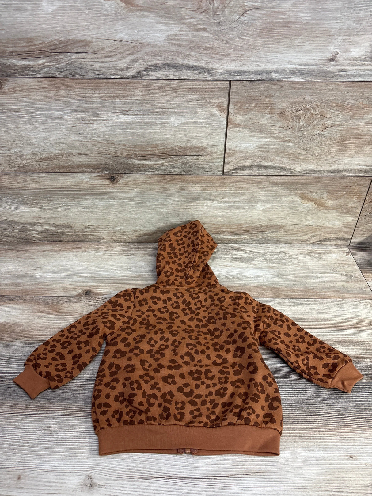 Brown kids hoodie with leopard print pattern on wood background