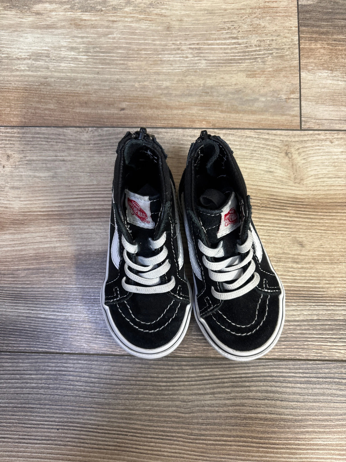 Overhead view of Vans Sk8-Hi Zip sneakers size 6C showing black high-top with white stripe and laces on wood floor