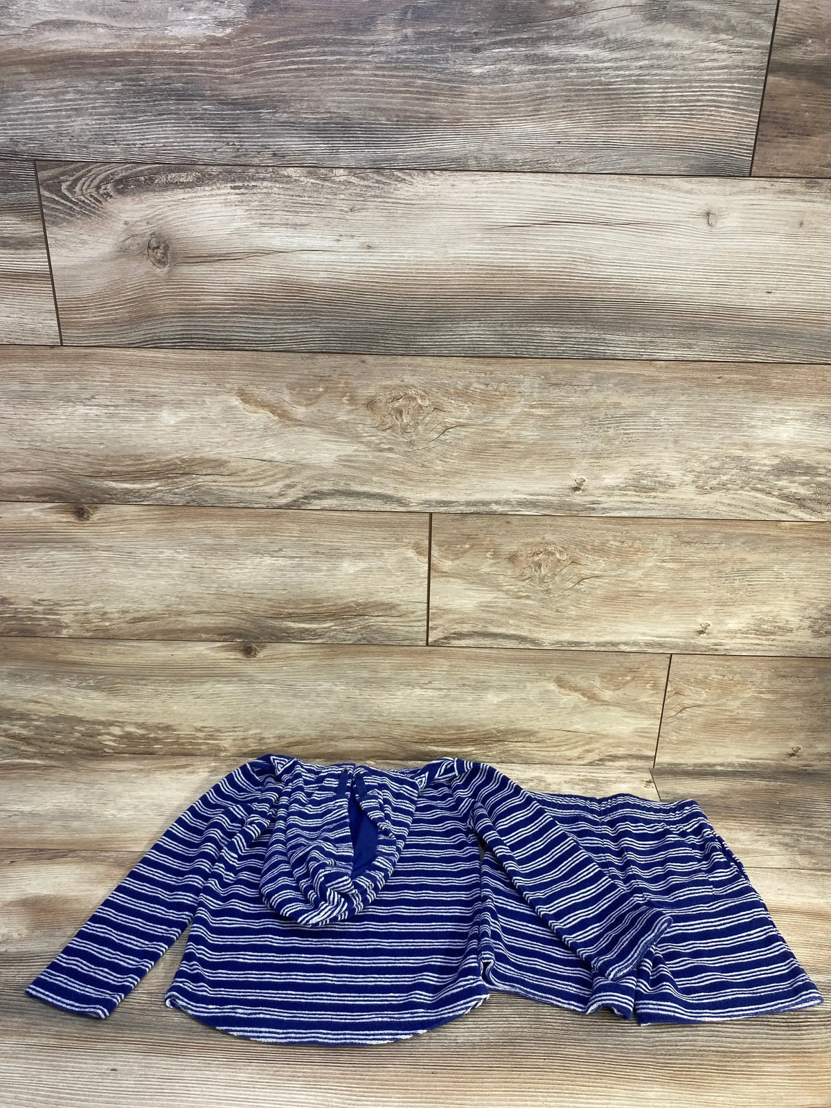 Flat lay of Janie and Jack 2pc Striped Terry Hoodie and Shorts Set in navy showcasing navy and white stripes with matching hooded top and shorts on wood plank floor