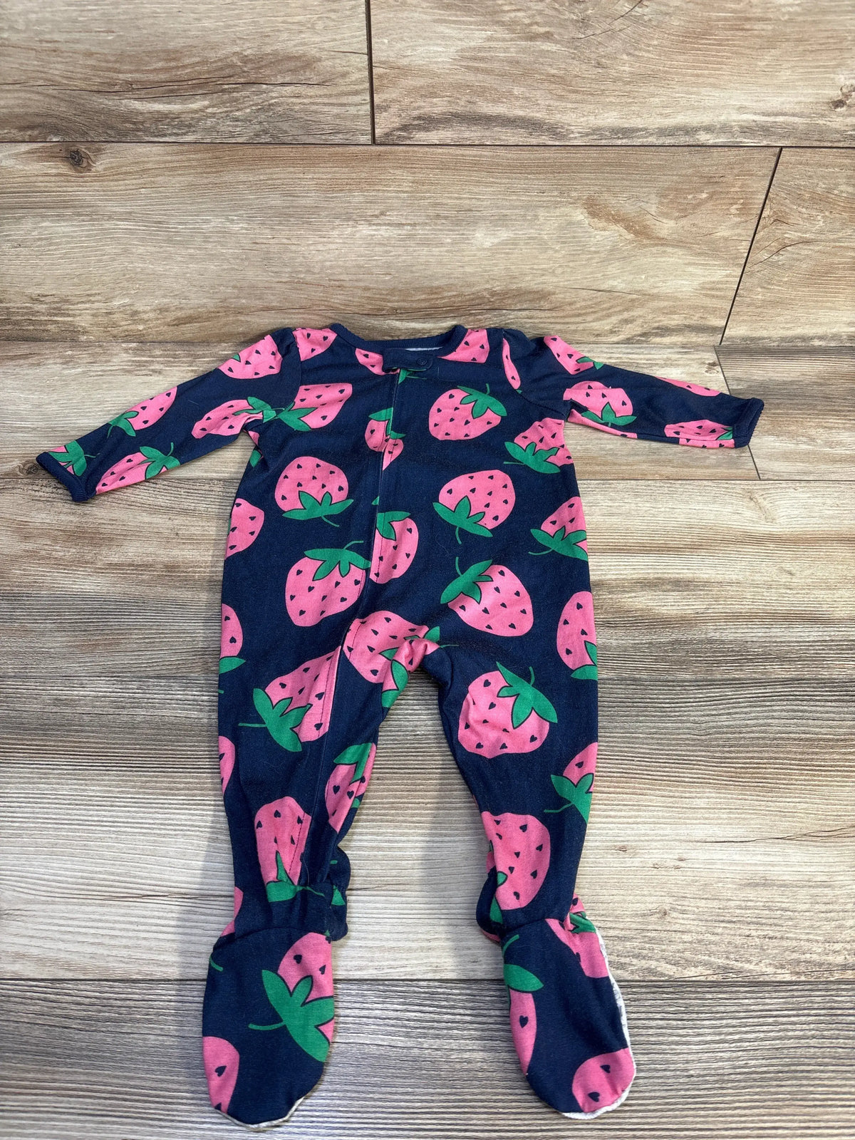 Front view of Simple Joys navy strawberry print sleeper showcasing footed legs on a wood-look floor