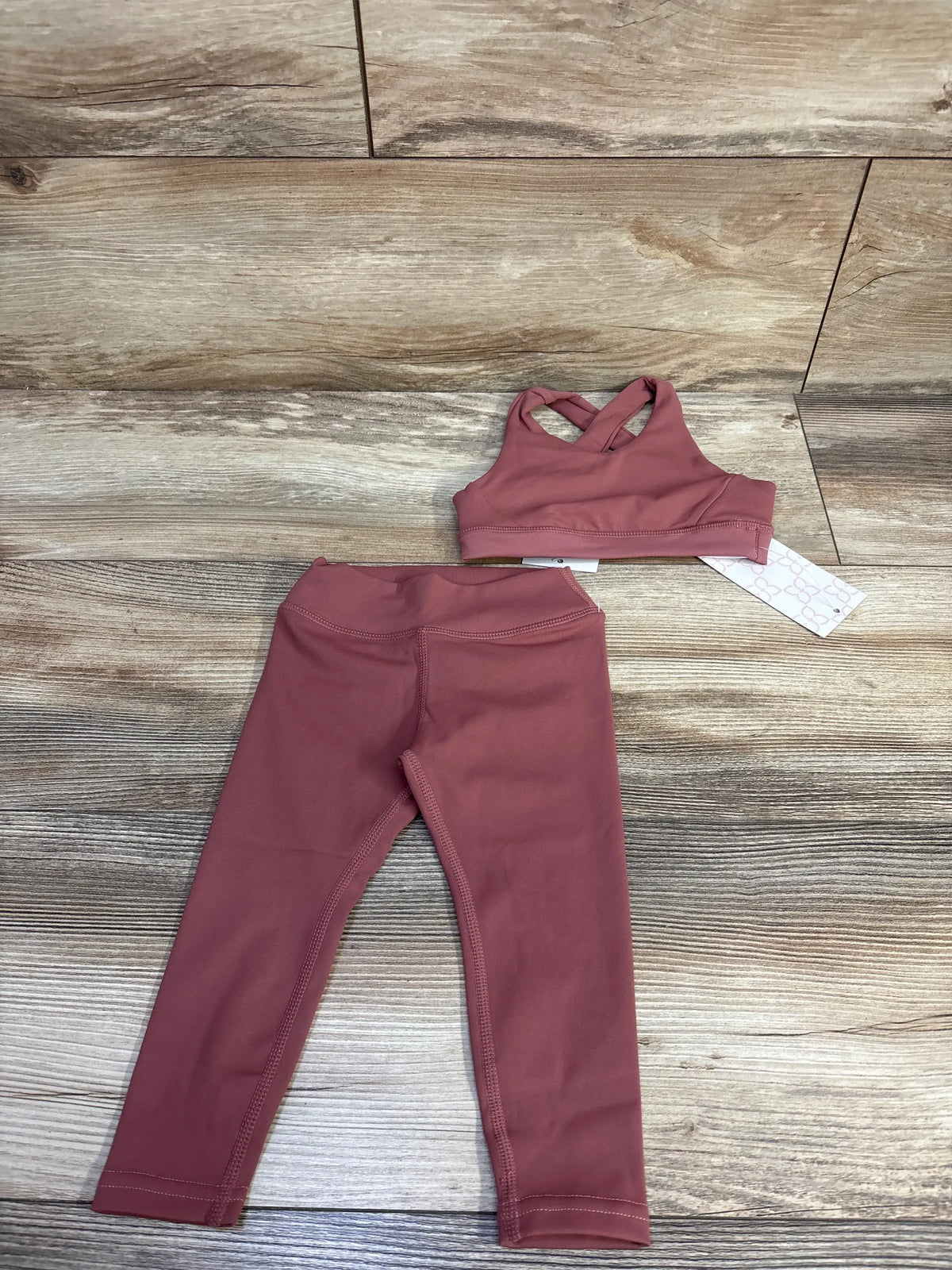 Flat lay of Bailey’s Blossoms red sports bra and leggings set, size 12 to 18 months, with crisscross straps