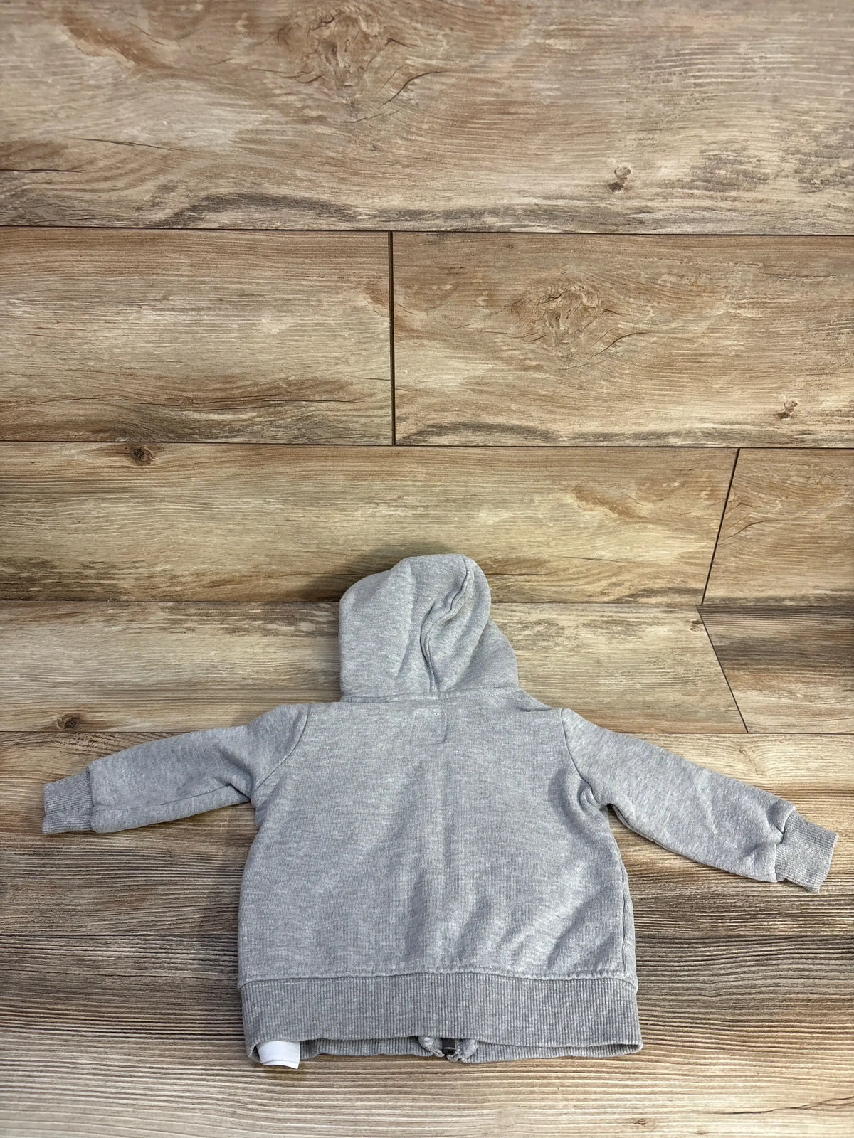 Back view of a grey Me n Mommy To Be full zip hooded jacket for infants on a wood background
