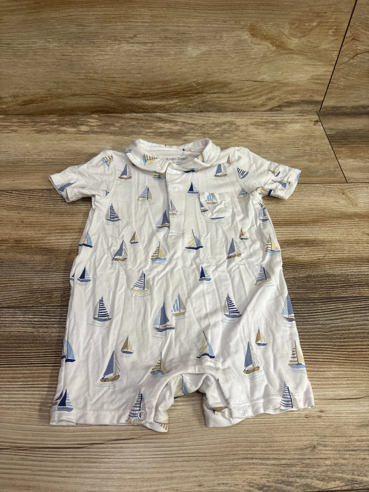 Front view of Angel Dear white bamboo polo shortie romper, size 6-12 months, with sailboat print and collar on wood flooring
