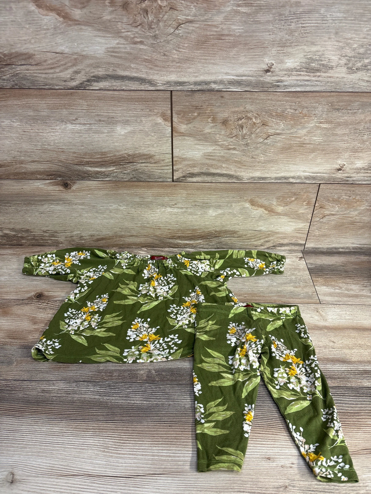 Green floral baby outfit set with long sleeve top and leggings on wood background