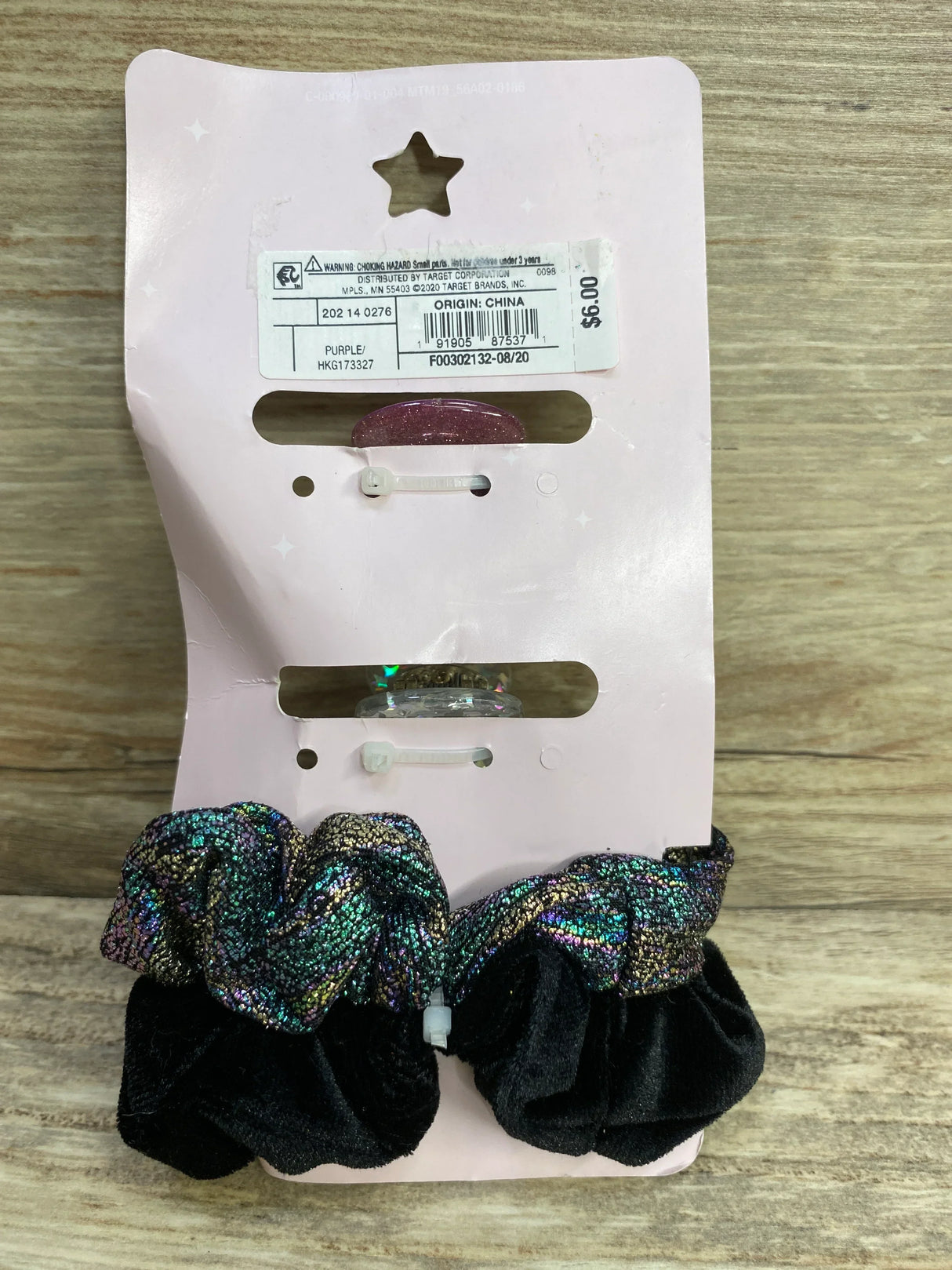 Set of two sparkly hair scrunchies in iridescent and black velvet on pink card with price tag