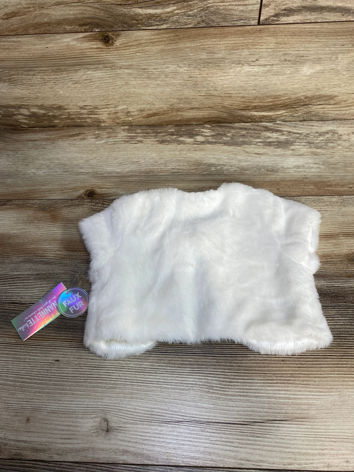 White faux fur animal vest with tags on wooden floor