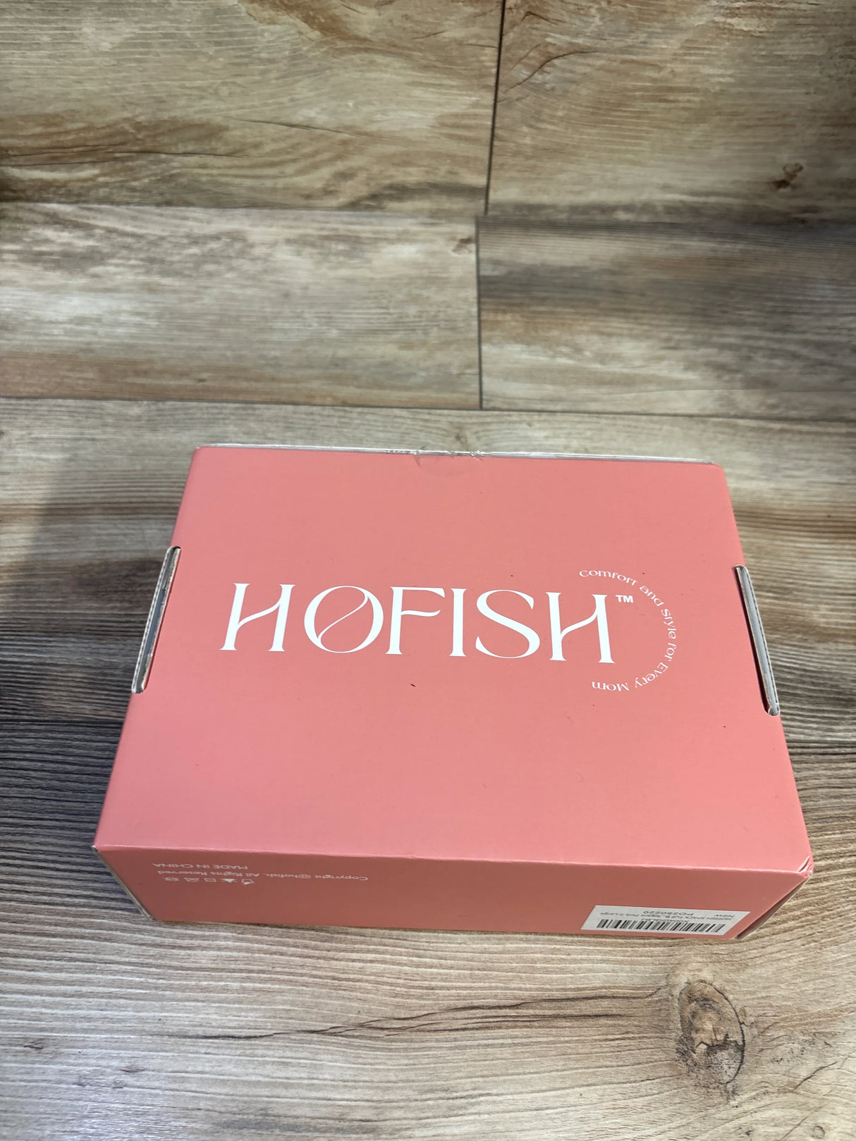 Top view of HOFISH nursing bra 3-pack box showing white HOFISH logo on coral box with wood tabletop background