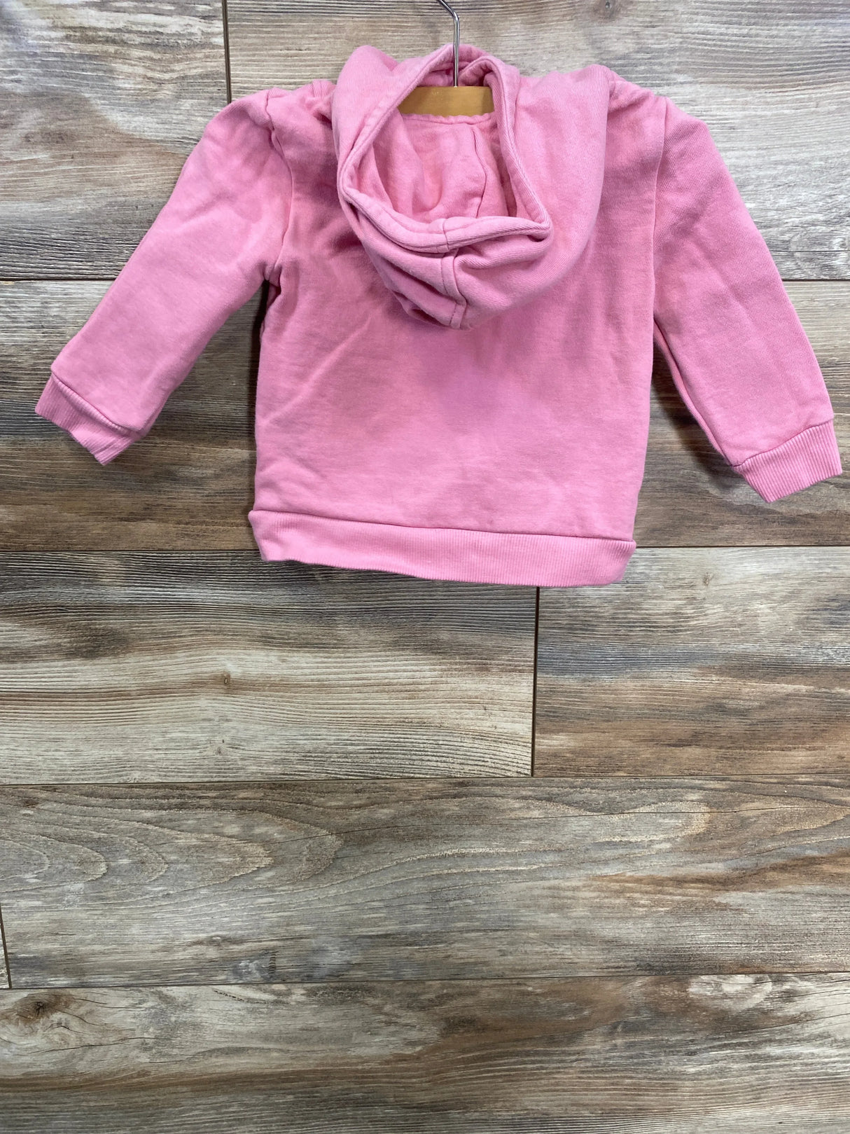 Pink toddler hoodie hanging on wooden background, kids clothing from children's resale store