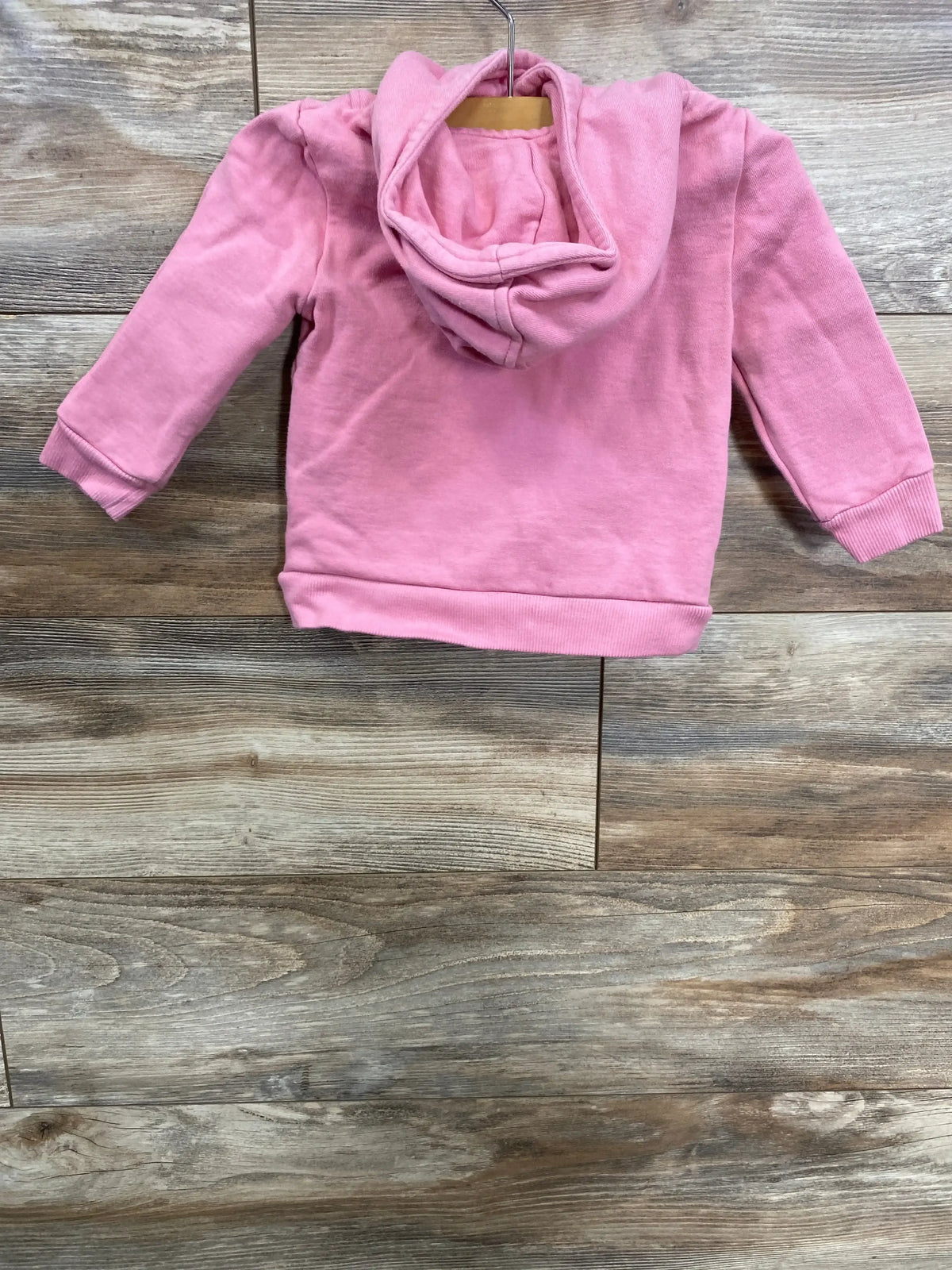 Pink toddler hoodie hanging on wooden background, kids clothing from children's resale store