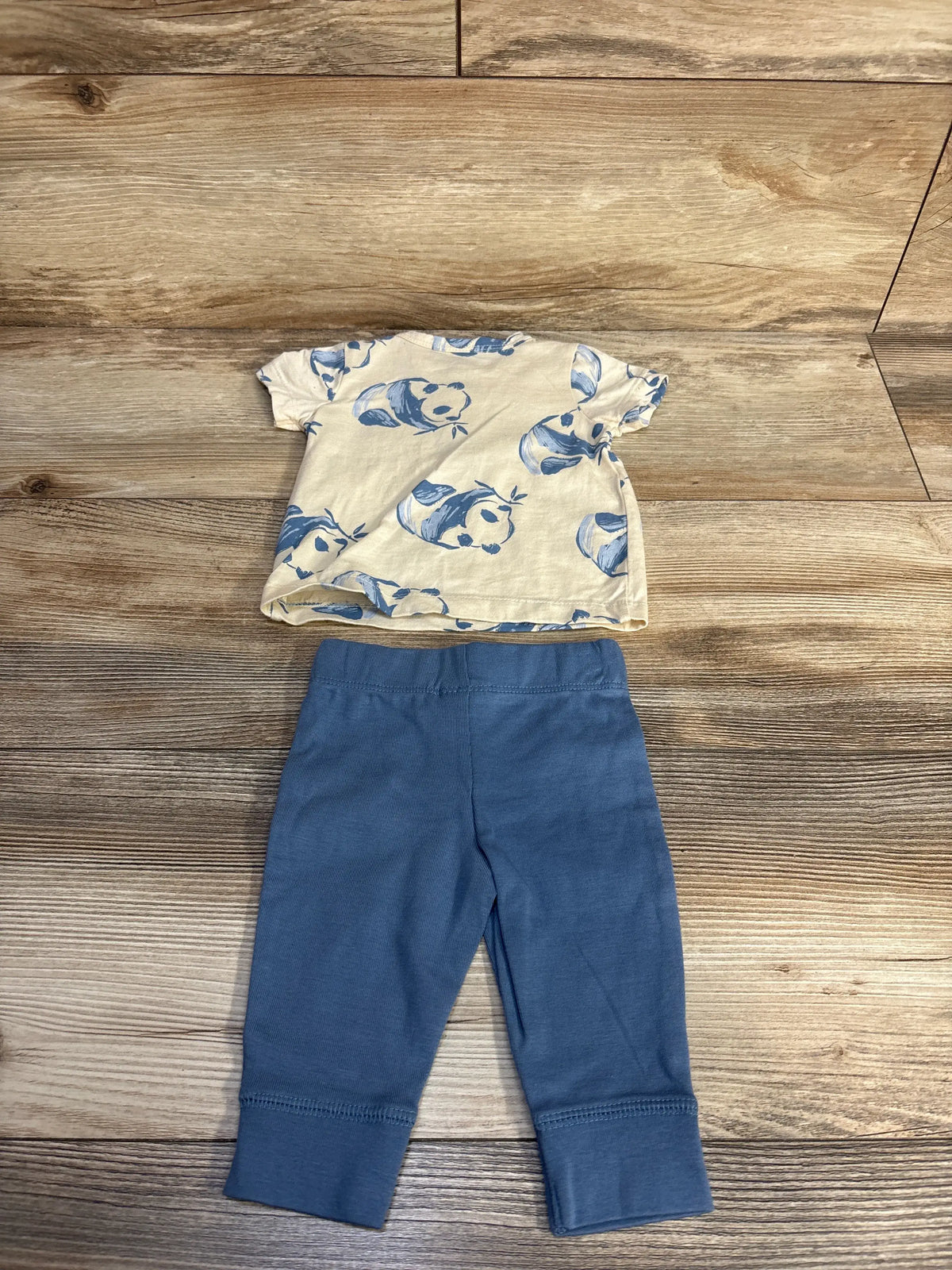 Top view of Carters two piece baby clothing set showcasing a panda print henley shirt and coordinating pants on wood grain