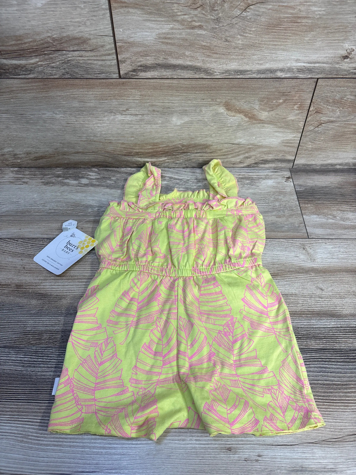 Front view of Burt’s Bees Baby tank shortie romper in lime, size 18 months, with pink leaf print on a wood floor
