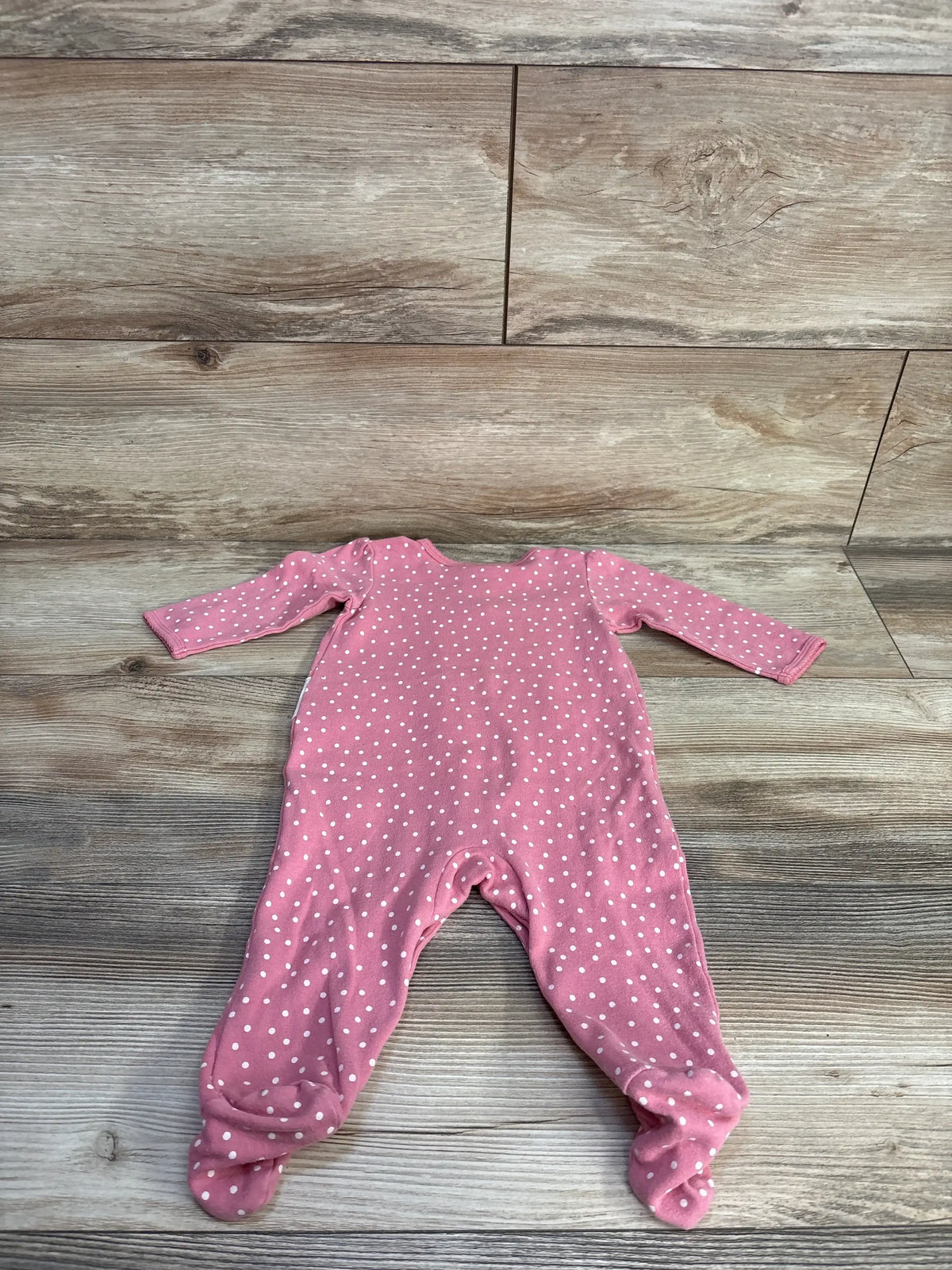 Back view of Carter’s Polka Dot Snap Sleeper size 6m showcasing dusty pink fabric with white dots and covered feet on wood plank floor