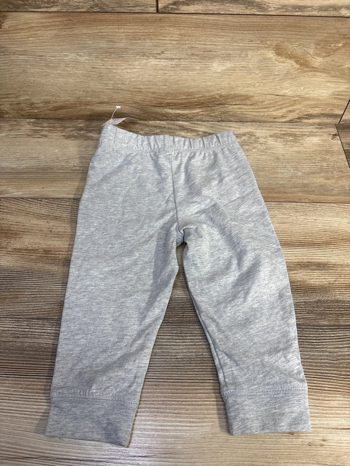 Front view of grey Wonder Nation pull-on jersey joggers, size 18 months, with elastic waistband and cuffed hems on wood