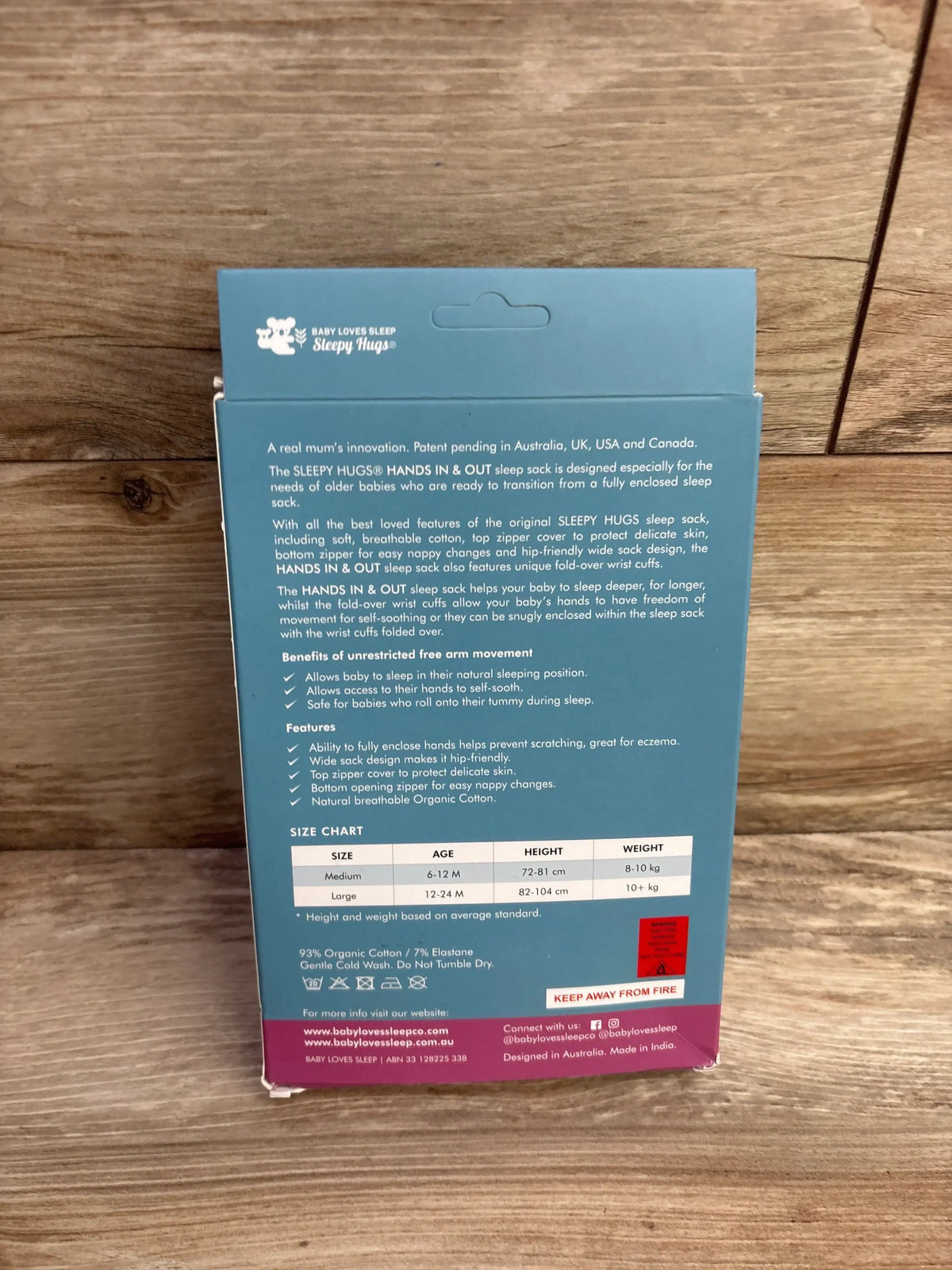Back of Sleepy Hugs Hands In & Out sleep sack box with size chart and product details on wood surface.