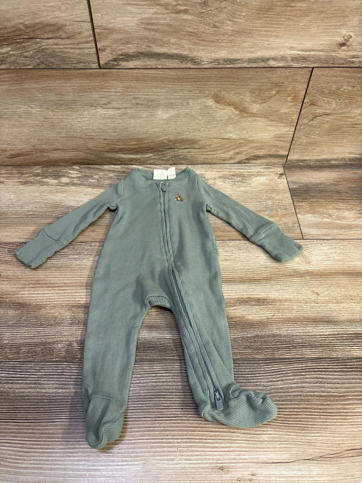 Front view of green Baby Gap ribbed sleeper showcasing long sleeves, zip front, and enclosed feet on wood-look flooring
