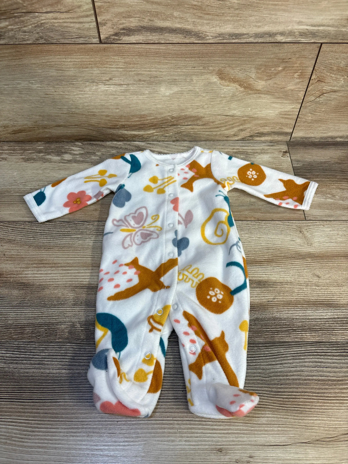 Front view of Carter’s white snap blanket sleeper showcasing snap closures and footed design on a wood floor