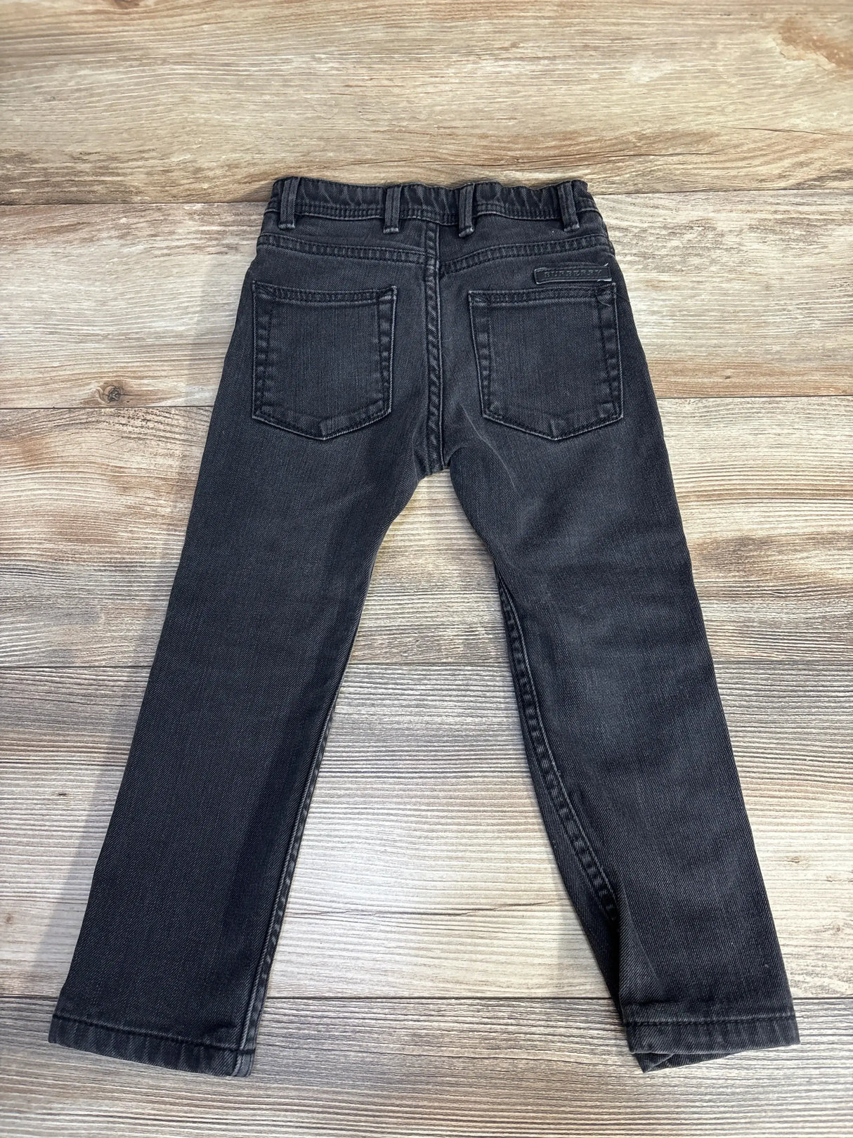 Front view of Burberry toddler jeans size 4T showing black denim, button and logo patch on white background