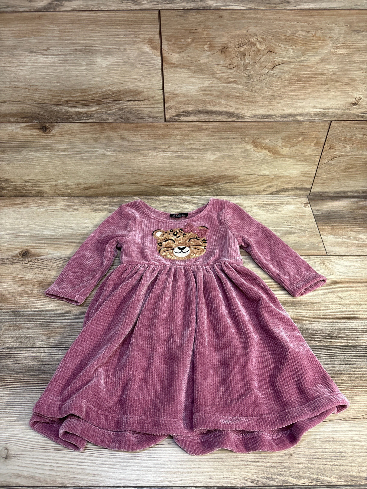 Front flat-lay of pink velvet toddler dress size 3T showcasing embroidered leopard face and gathered skirt on wood floor