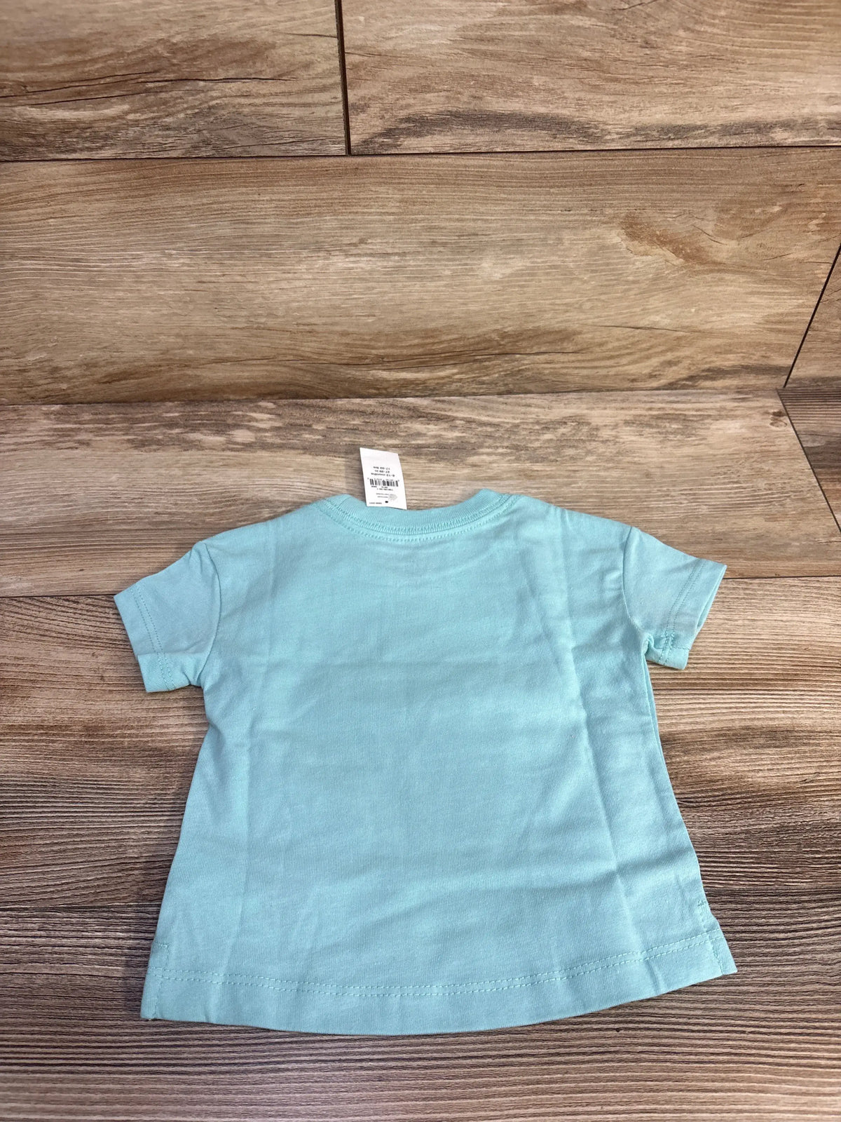Back view of blue Baby Gap short-sleeve shirt showcasing crew neckline and hem on a wood floor