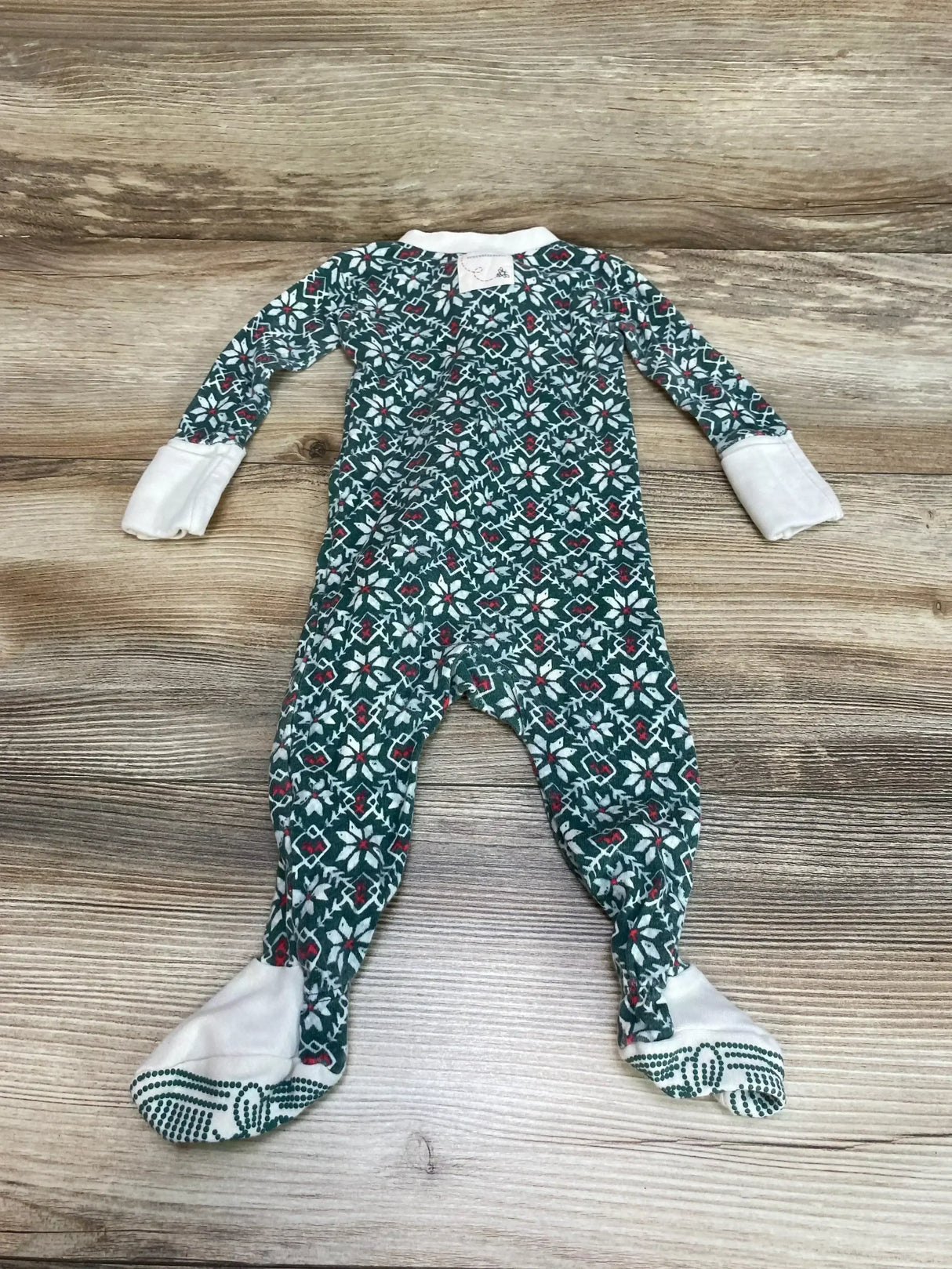 Flat lay of green Burt’s Bees Baby footed organic sleeper with fold over mitts and non-slip soles on wood background