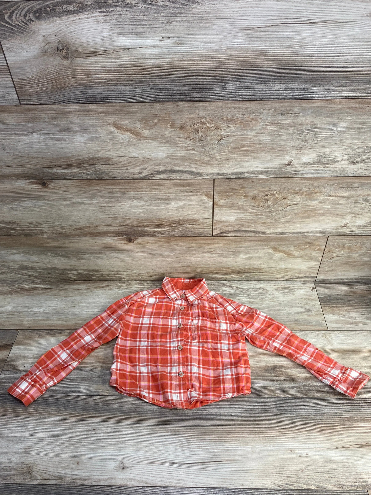 Orange and white plaid long sleeve button-up shirt on wooden floor background