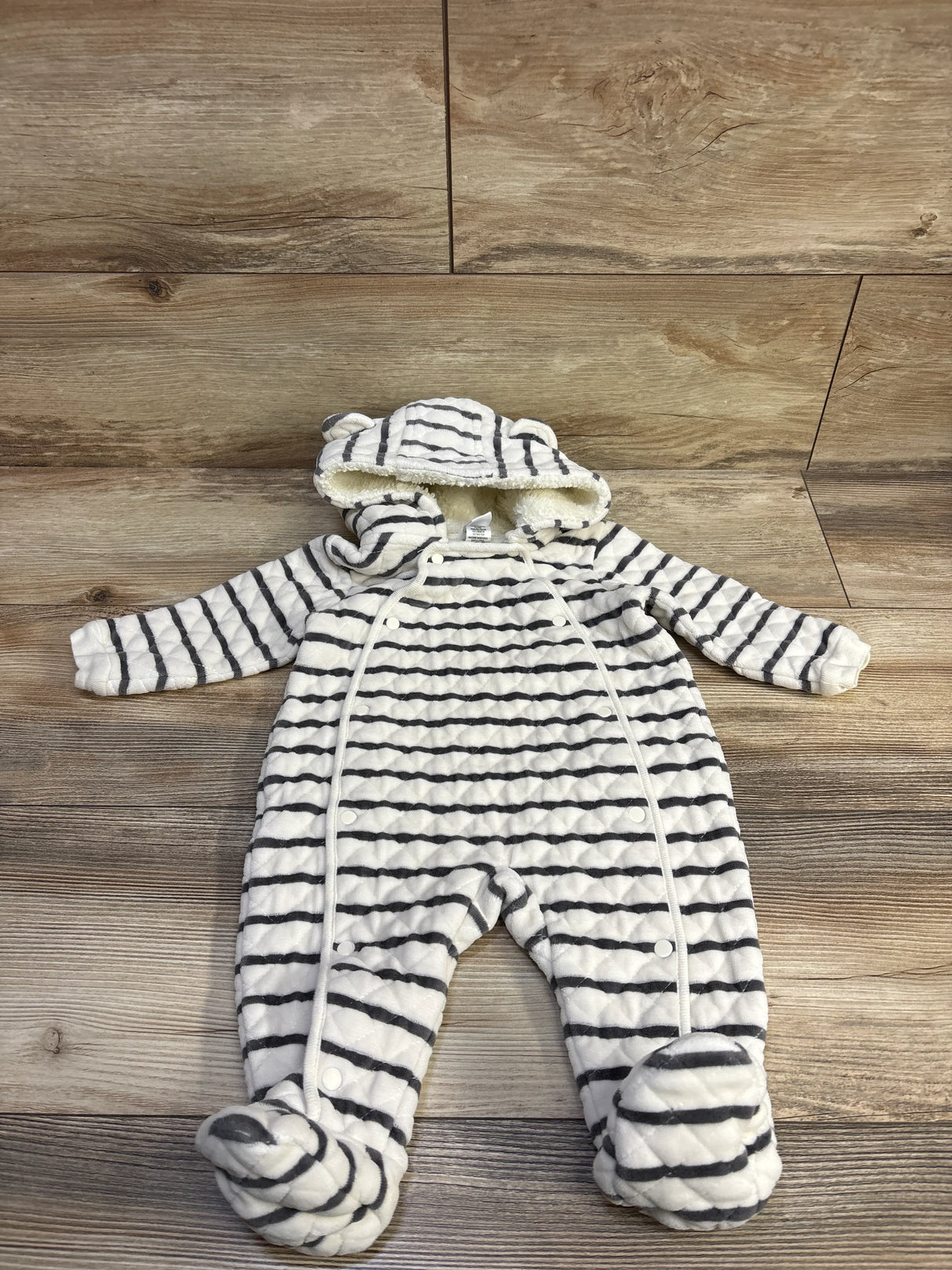 Flat lay white/gray striped quilted baby bunting, hood with ears, sherpa lining, snap-front closure and footed on wood floor