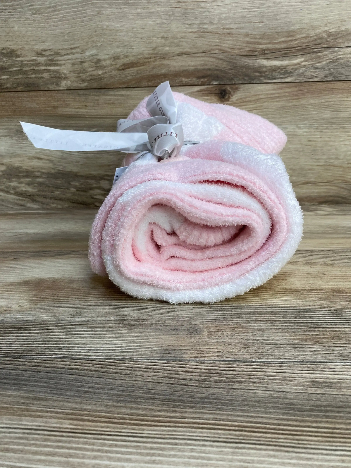 Rolled front view of pink Little Giraffe chenille baby blanket showing soft plush texture and tied ribbon on wood background