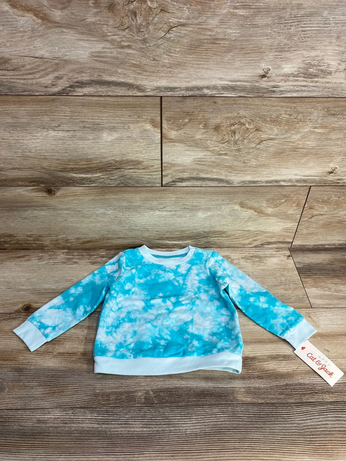 Blue and white tie dye kids long sleeve shirt on wood background with clothing tag