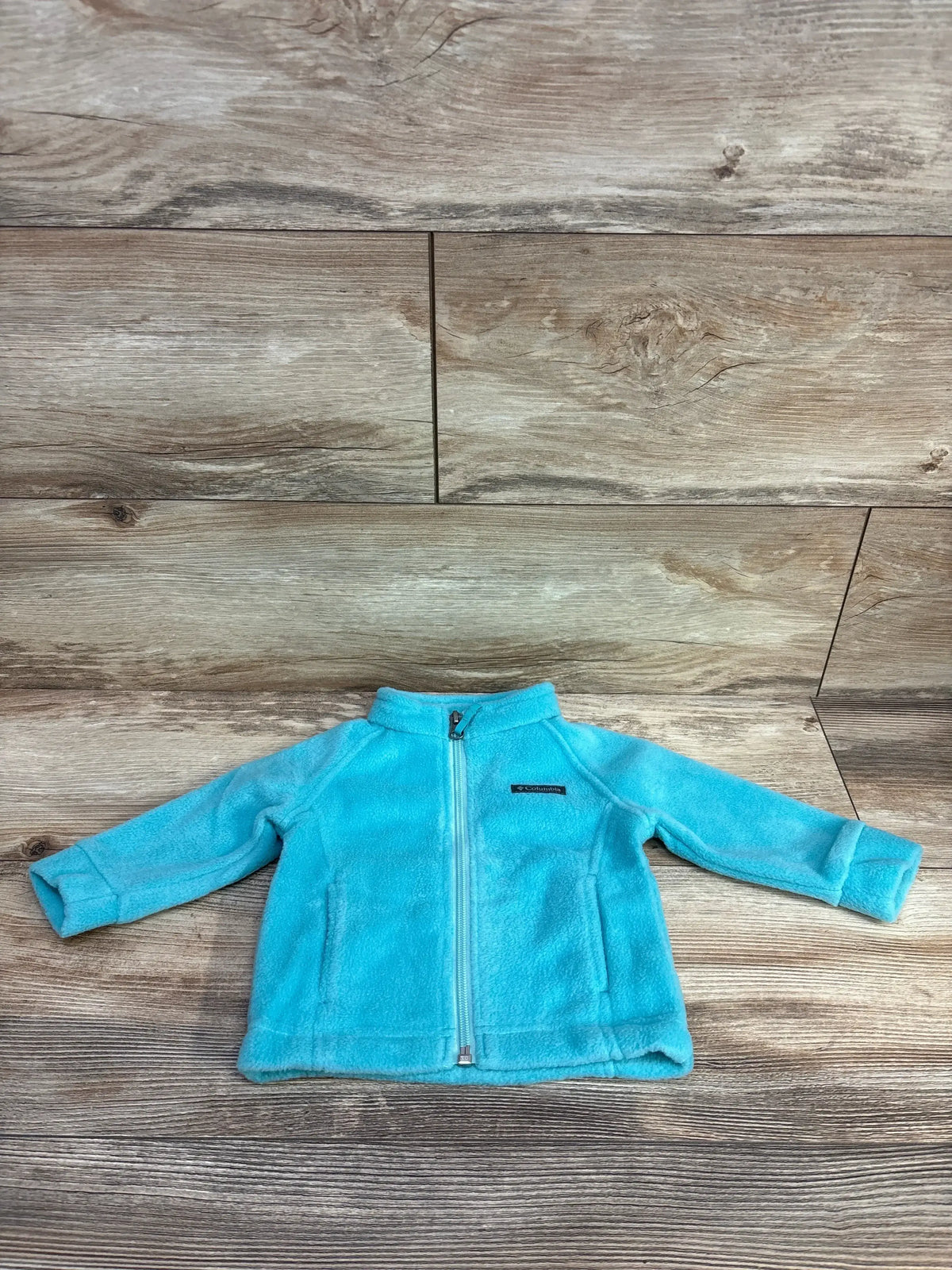 Light blue Columbia fleece jacket for toddlers laid flat on wooden floor