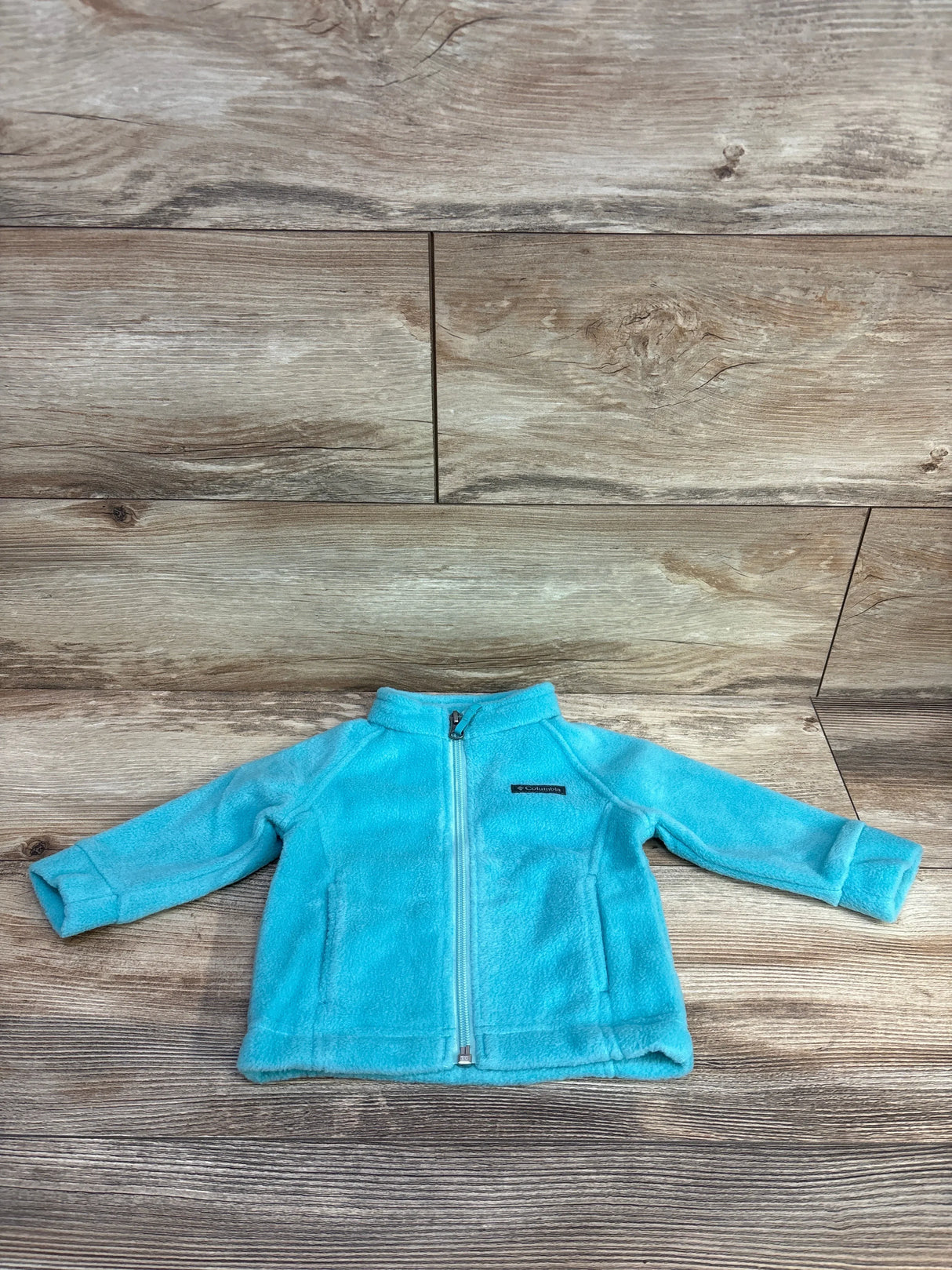 Light blue Columbia fleece jacket for toddlers laid flat on wooden floor