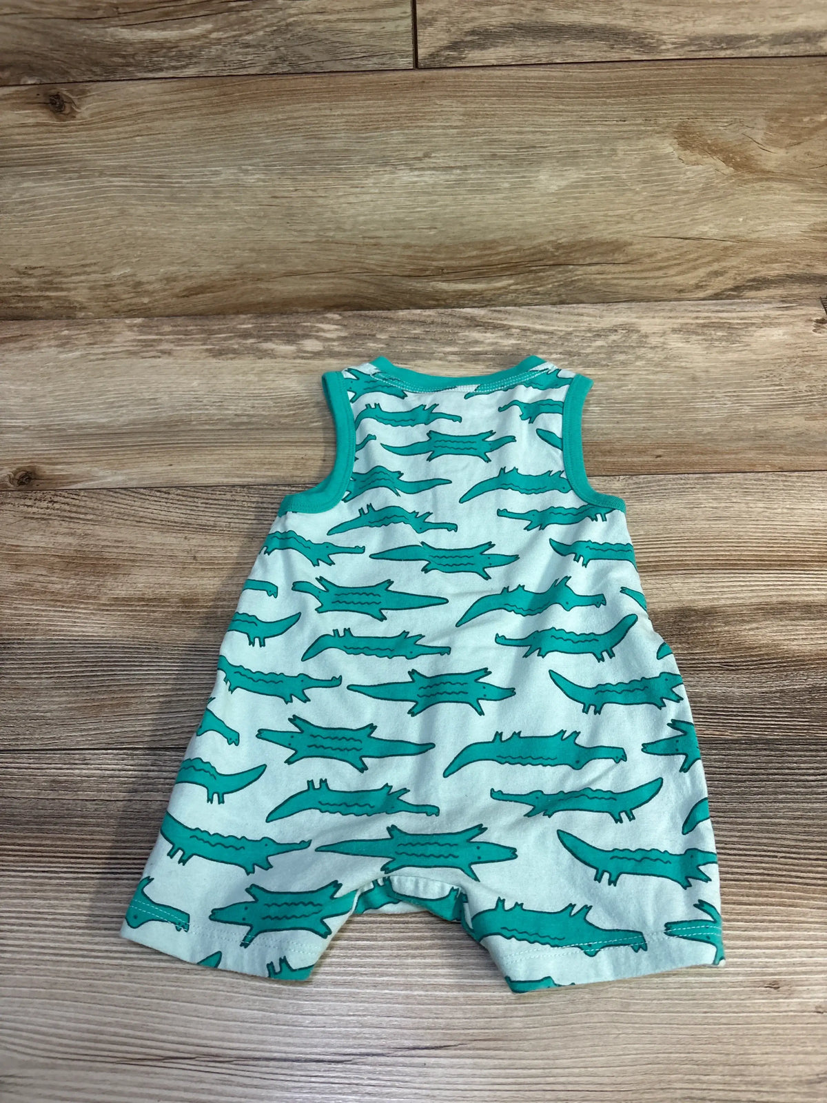 Front view of Cat and Jack Henley Shortie Romper in green with alligator print on a wood-grain background