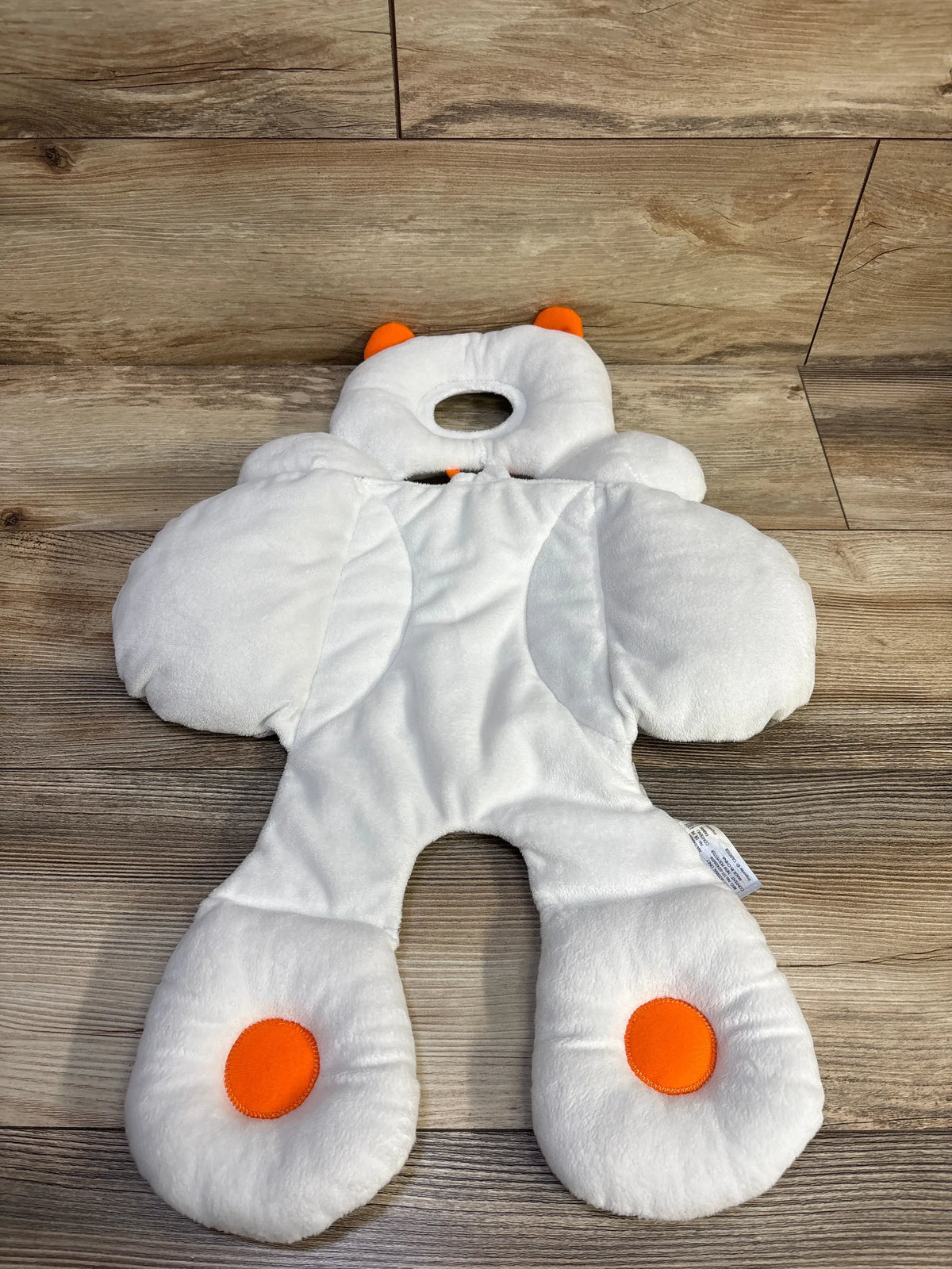Top view of BenBat Total Body Baby Support Pillow for stroller or car seat showcasing head, arm, and leg support on a wood floor
