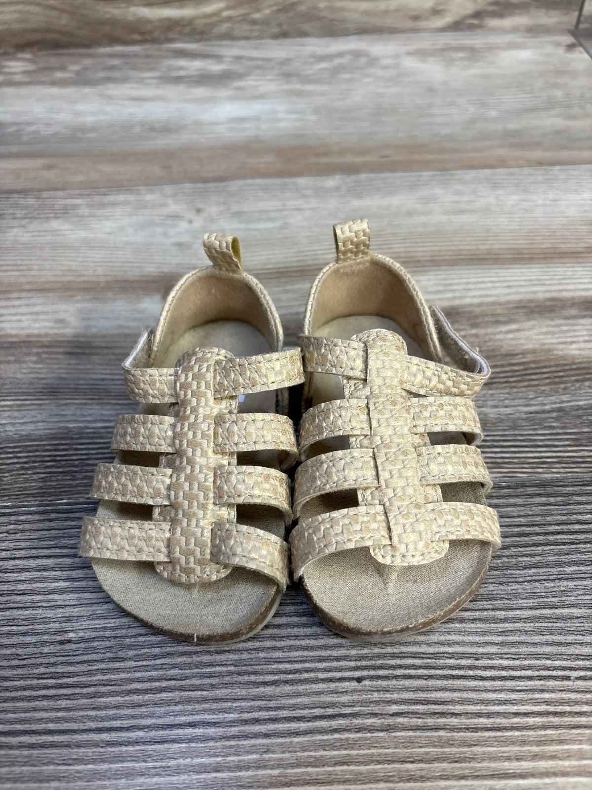 Front view of Carter’s strappy sandals showcasing brown textured straps and open toes on a wood-grain floor