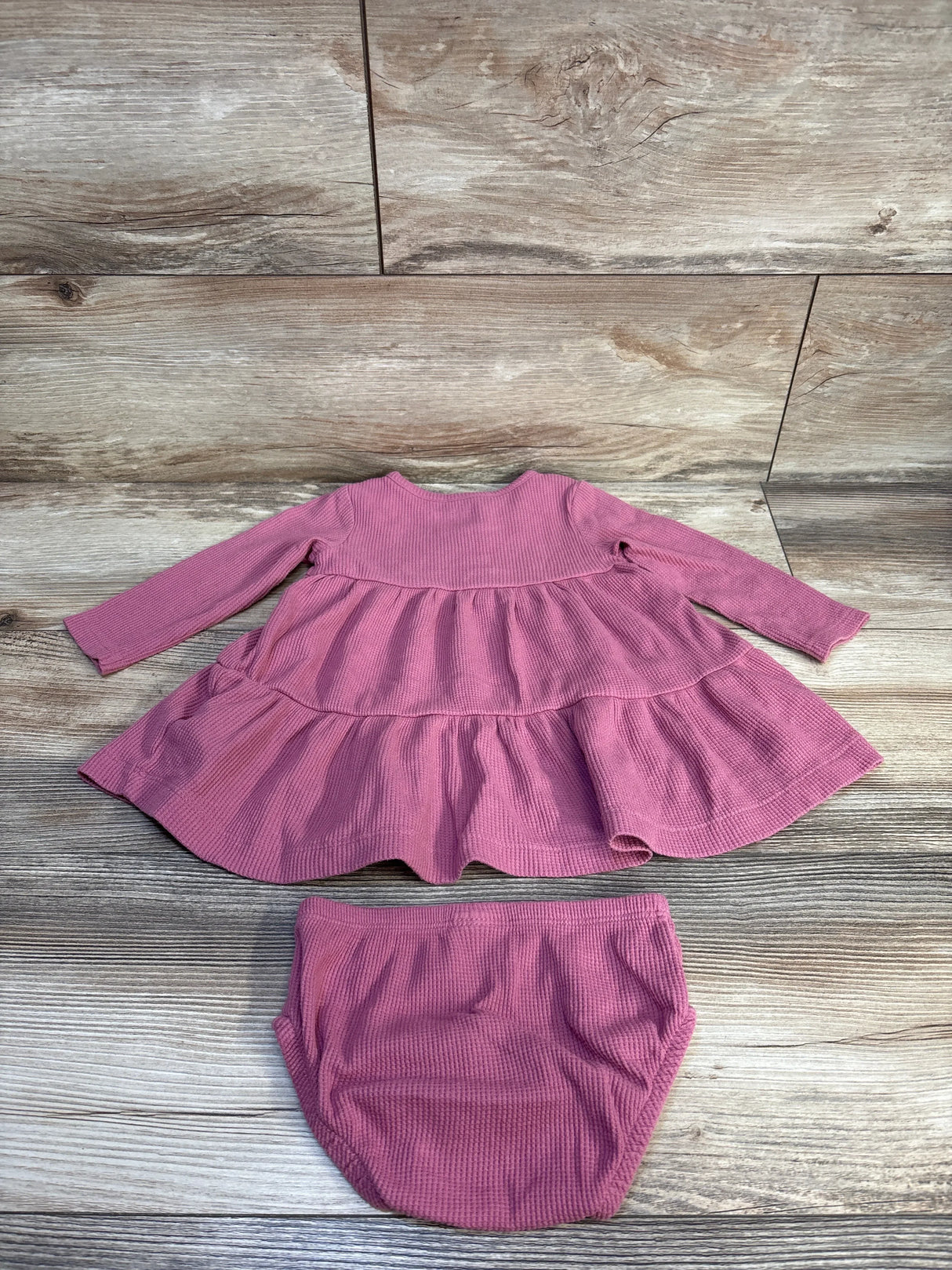 Pink ribbed baby dress with matching bloomer set on wooden background