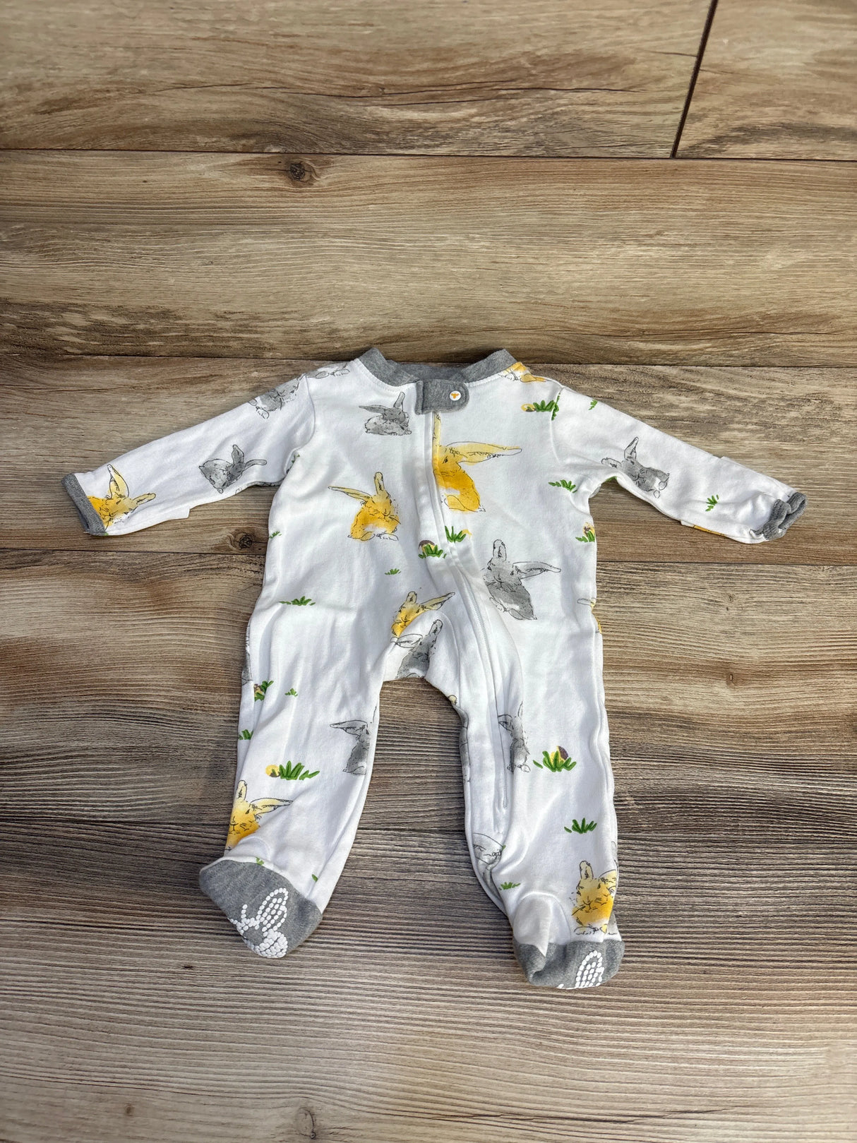 White baby sleeper with yellow and gray bunny print on wood background