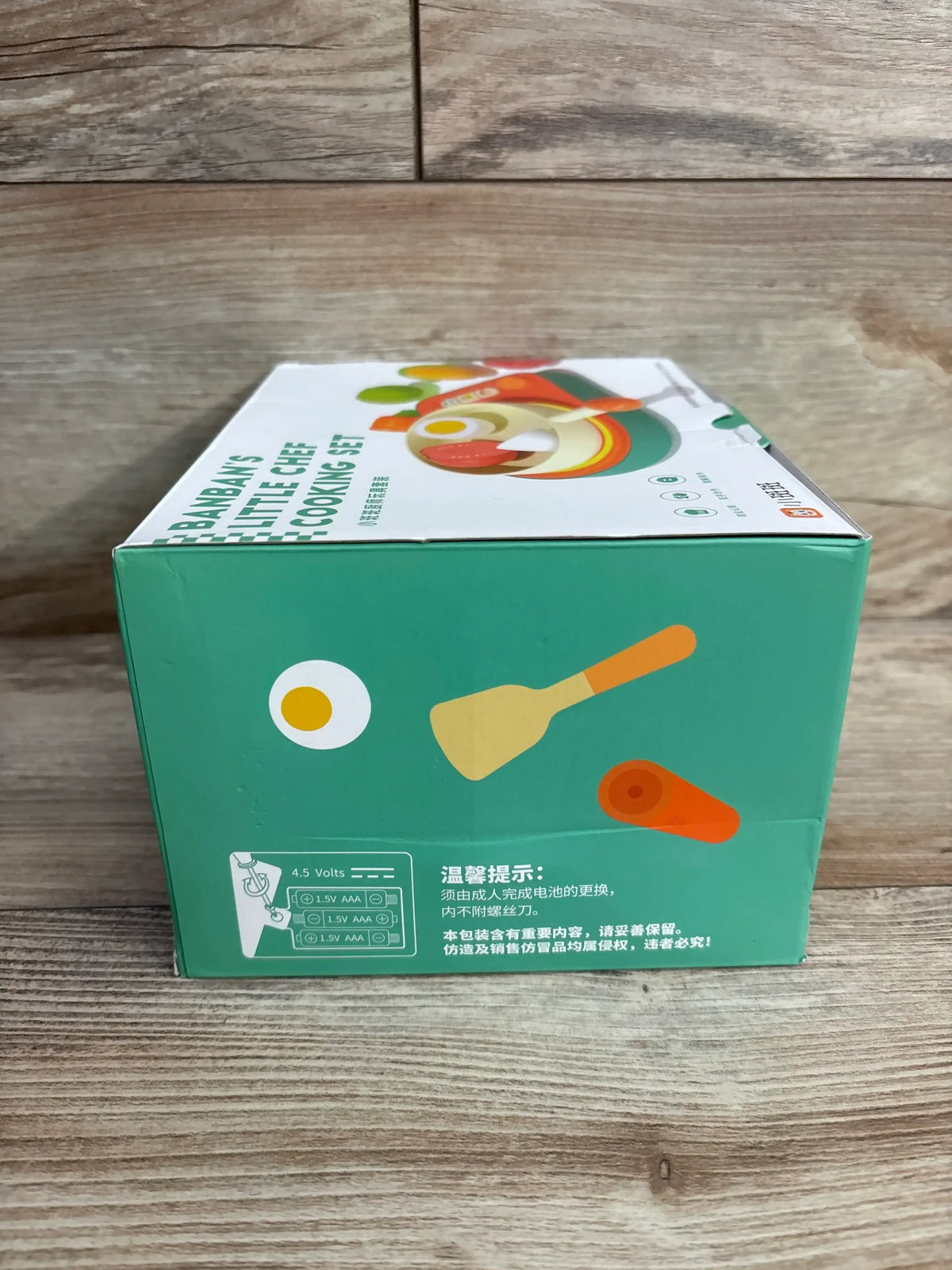 Front-left view of Banban’s Little Chef Cooking Set box showing green packaging with egg, spatula, and carrot illustrations on a wood surface