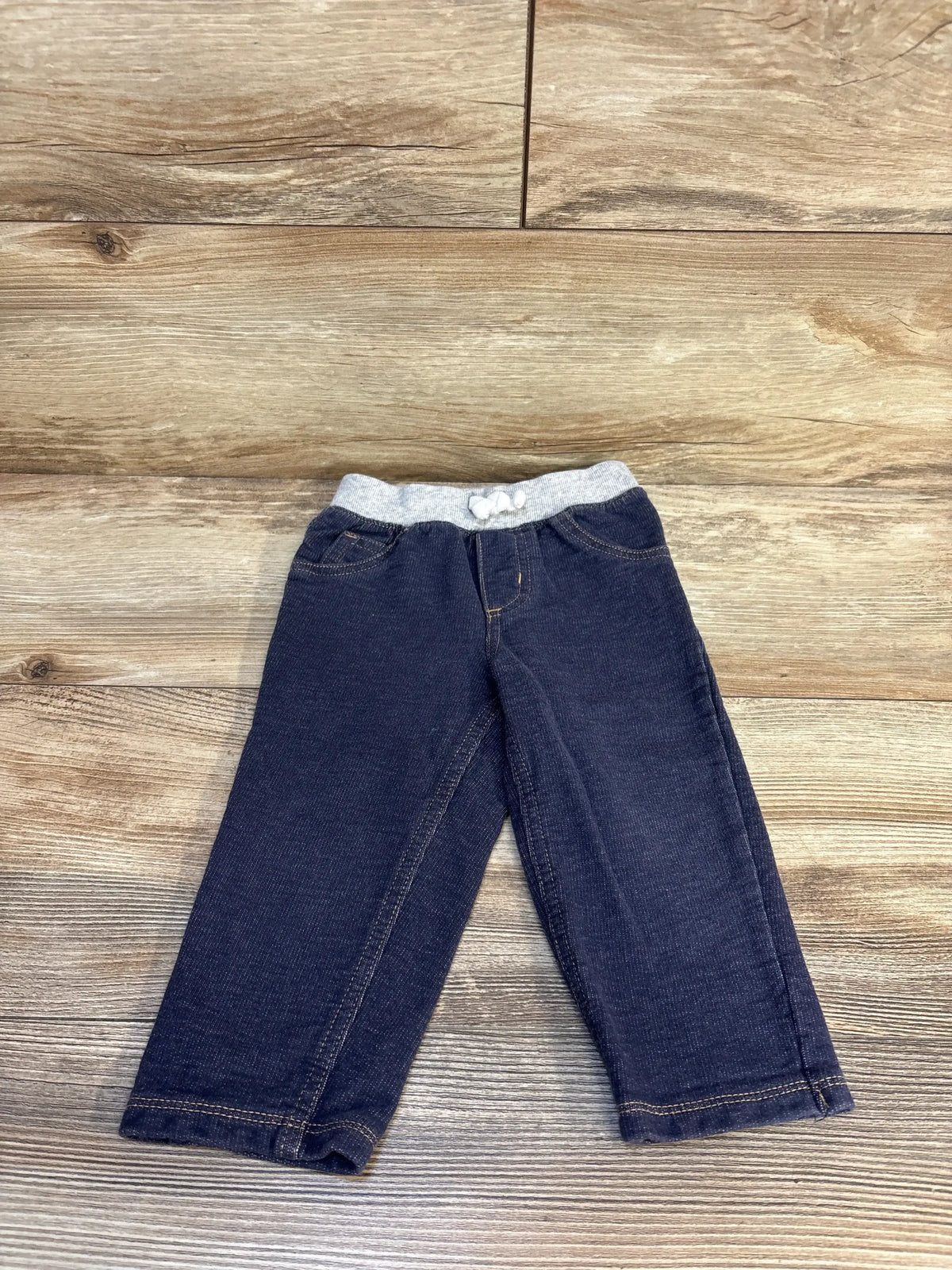 Navy blue baby pants with gray elastic waistband on wood background, gently used kids clothing