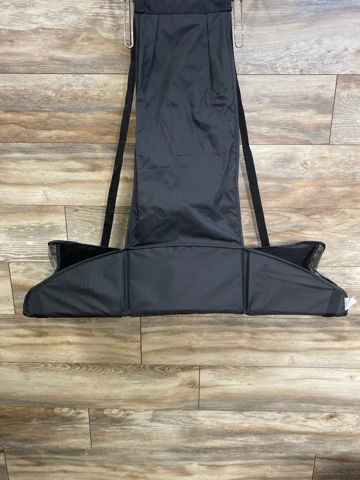 Overhead view of Baby Change-N-Go portable hanging changing station with hooks, side straps, and mesh pockets on a wood floor
