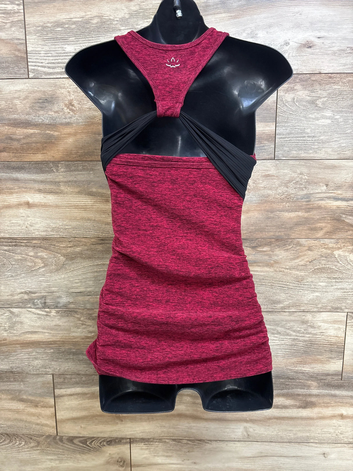 Front view of red spacedye maternity racerback tank with black crossover back and ruched sides on mannequin, wood background