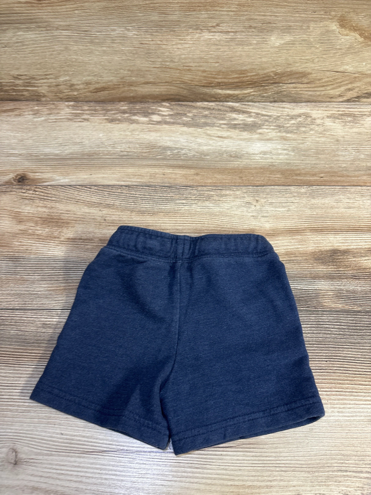 Flat lay of navy Cat & Jack knit toddler shorts showing elastic waistband and knit fabric texture on wood background
