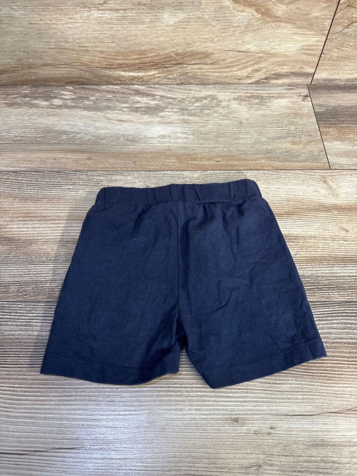 Front view of Dirkje drawstring shorts showcasing navy fabric and elastic waist on a wood-look floor