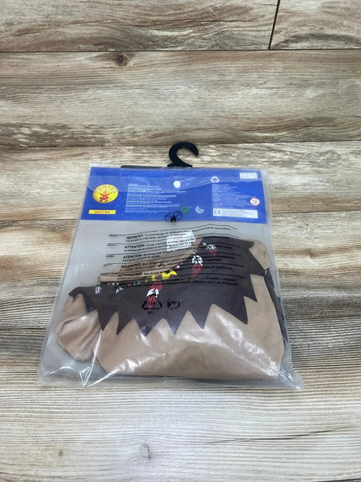 Front view of Rubies warrior costume, size 8 to 10, in packaging with jagged dark trim and red emblem on wood grain floor