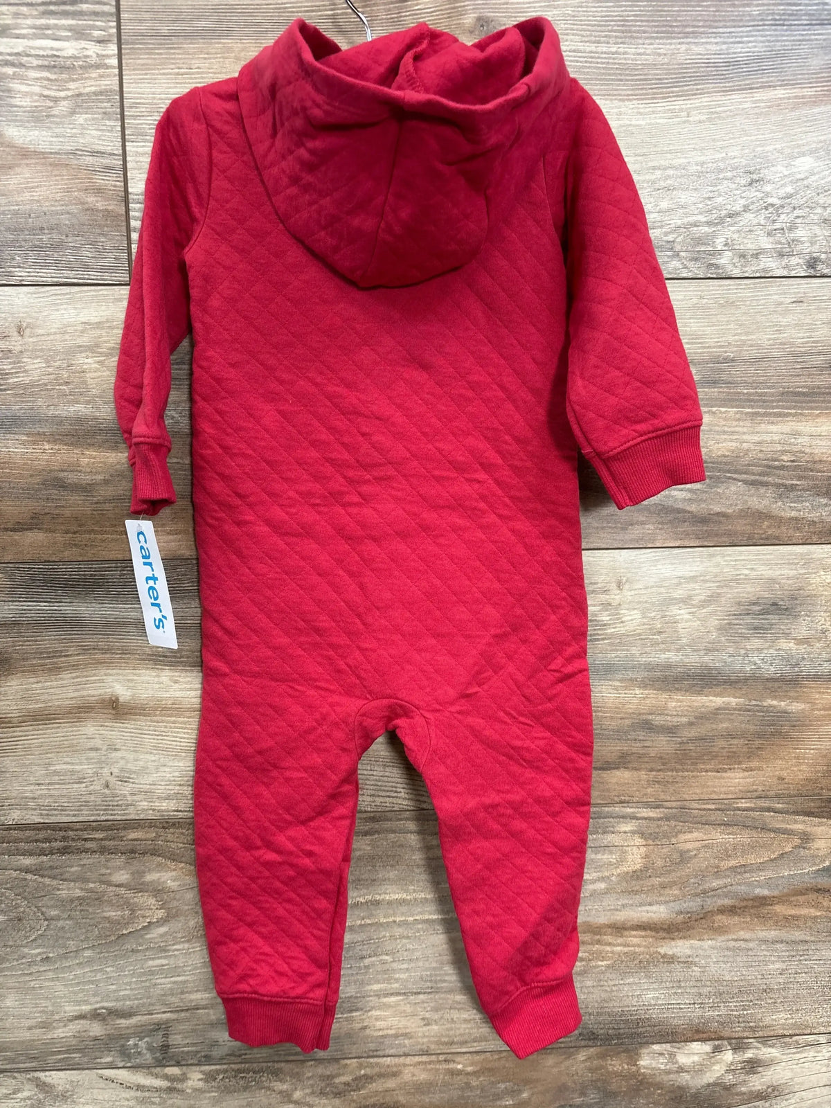 Red quilted baby jumpsuit with hood and long sleeves on wooden floor, Carter's brand tag visible