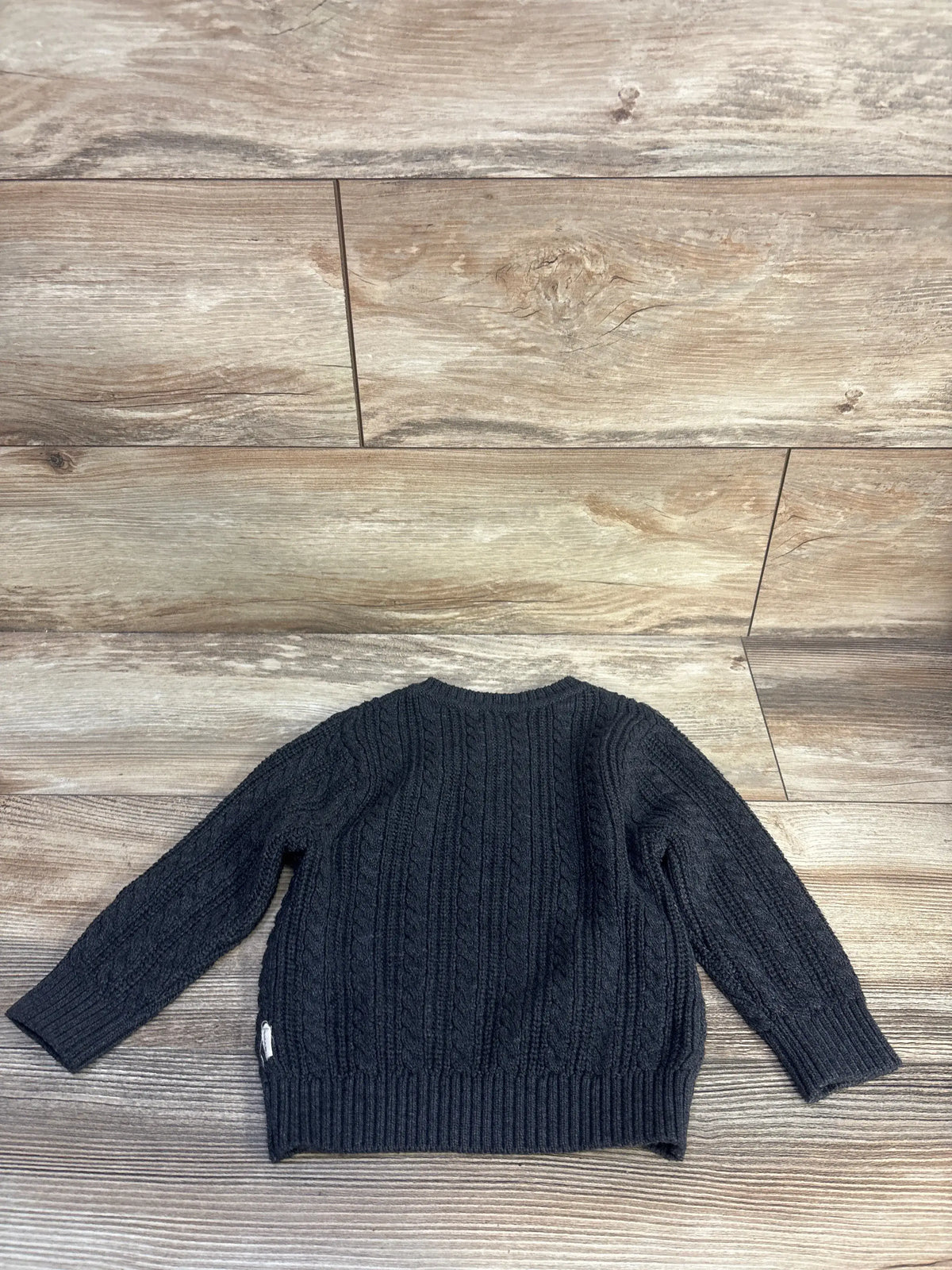 Front view of grey Tahari cable knit henley sweater in size 18 months showcasing textured cable knit pattern on a wood plank background