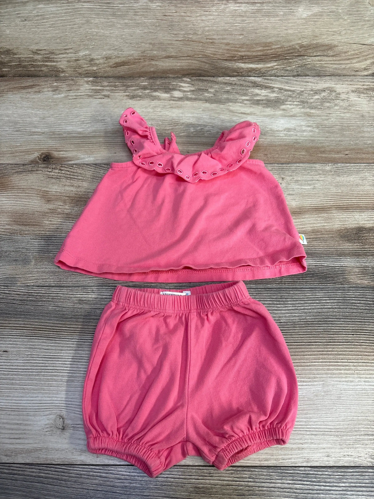Front view of pink two-piece top and shorts set with a ruffled eyelet neckline and elastic-waist shorts on a wood surface