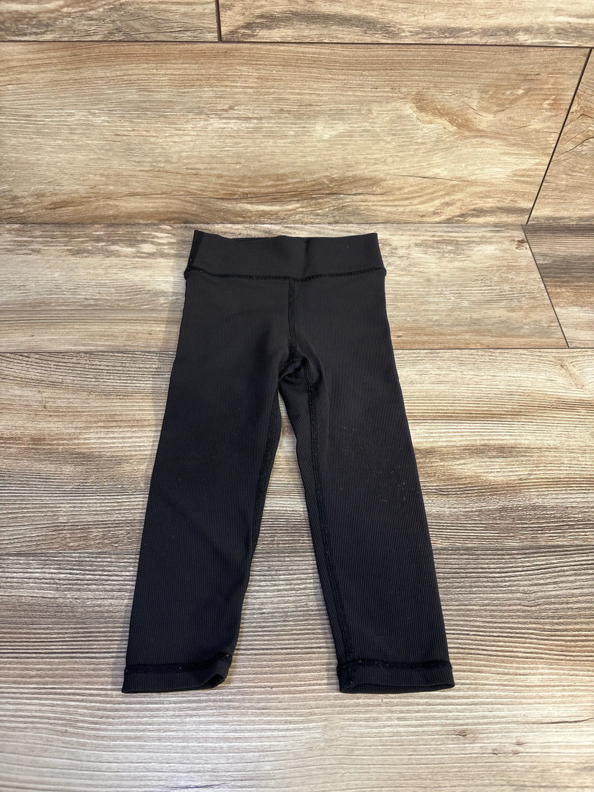 Front view of Little Bipsy Active Ribbed Leggings in black, showcasing ribbed texture and elastic waistband on a wooden floor
